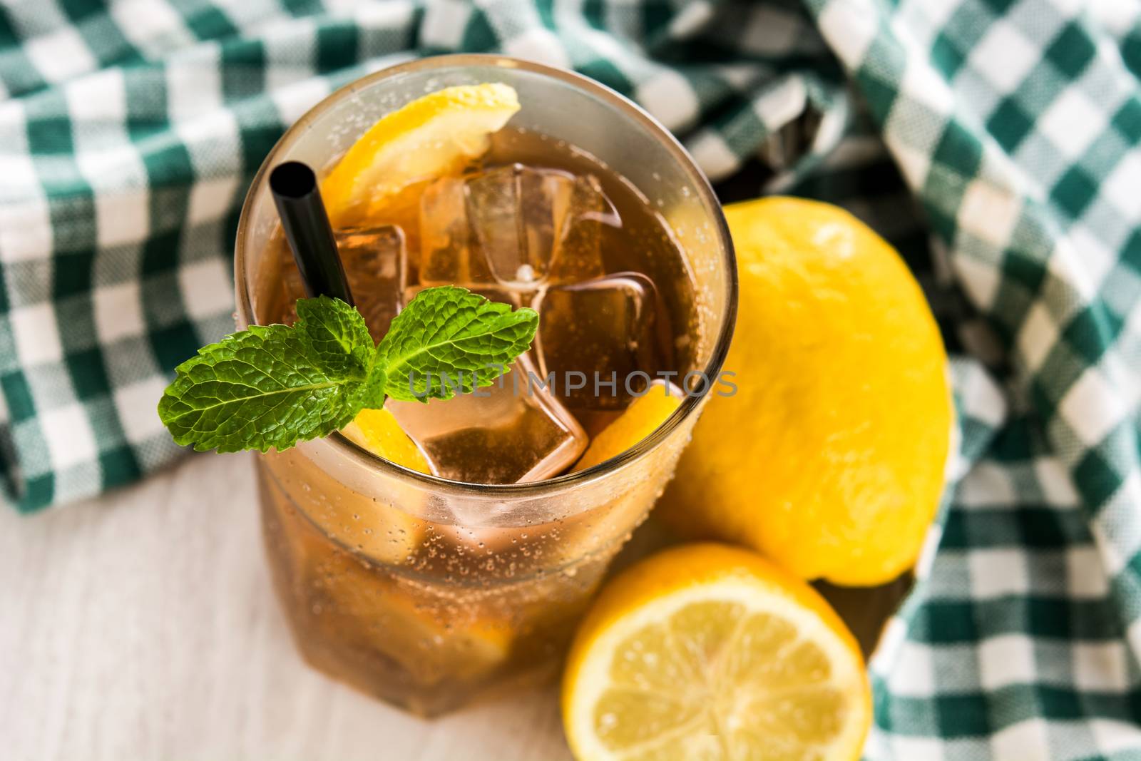 Iced tea drink with lemon in glass and ice on white wooden table by chandlervid85