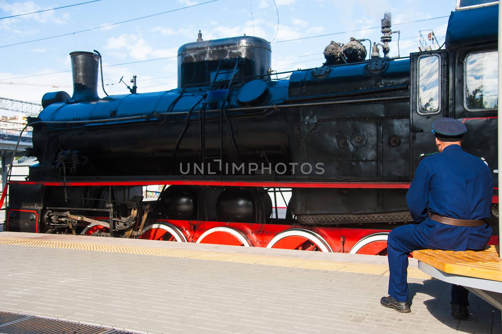 Vintage black steam locomotive. The train arrived at the station. Driver on the platform