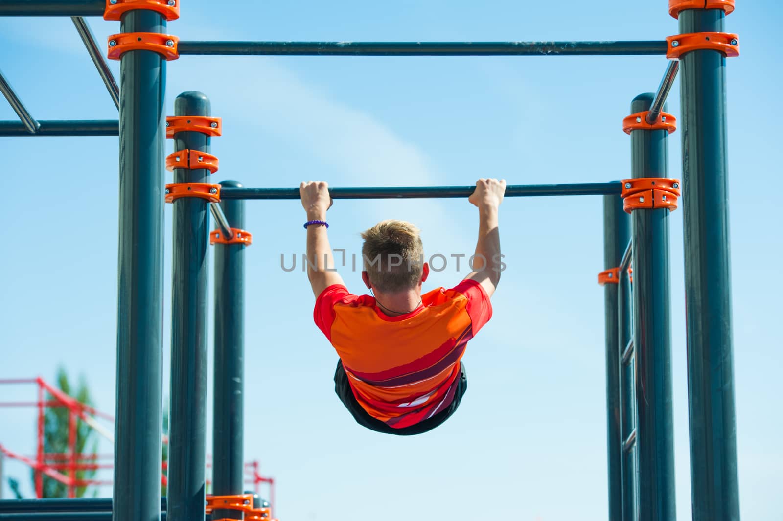Young man exercising on horizontal bar outdoors. Calisthenics workout.