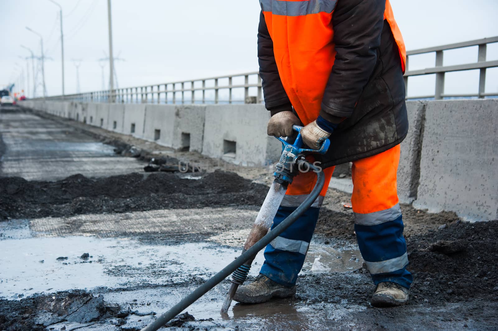 Road worker removes old asphalt with a jackhammer during road construction
