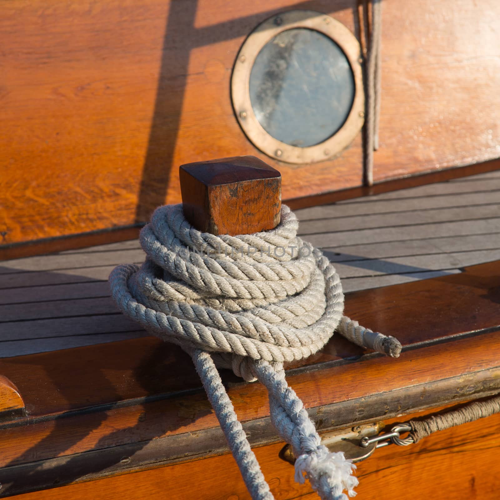 Detail of an old wooden sailing ship with rope and porthole