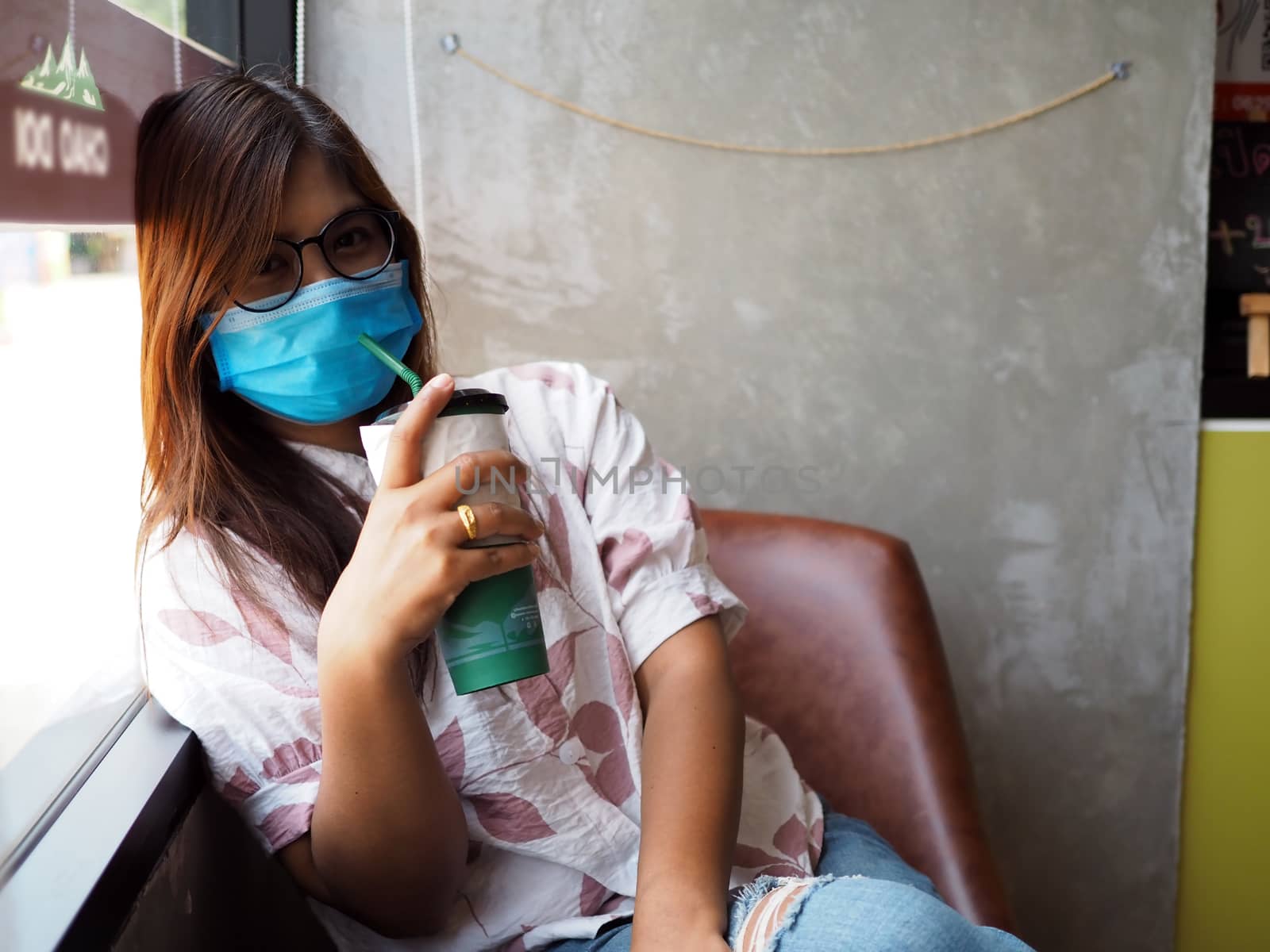 Woman with face protective mask looking at the camera in cafe. n by Unimages2527