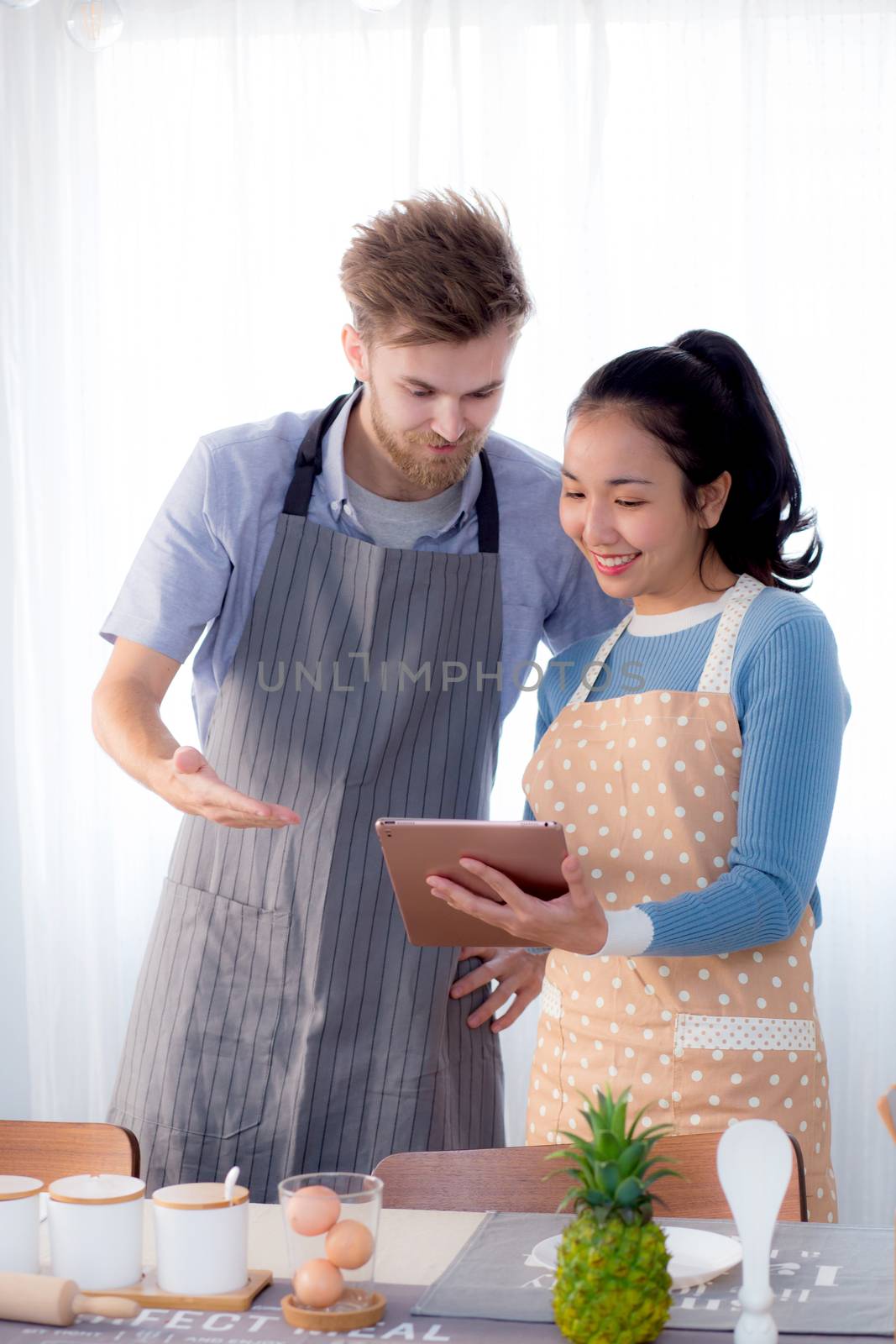 Young couple in kitchen looking at tablet - Man and girl using digital tablet in kitchen.
