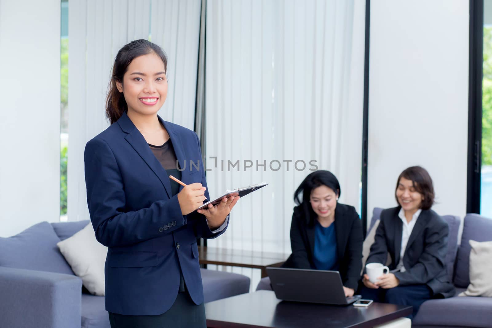 businesswoman standing with notebook with colleagues in team on background.