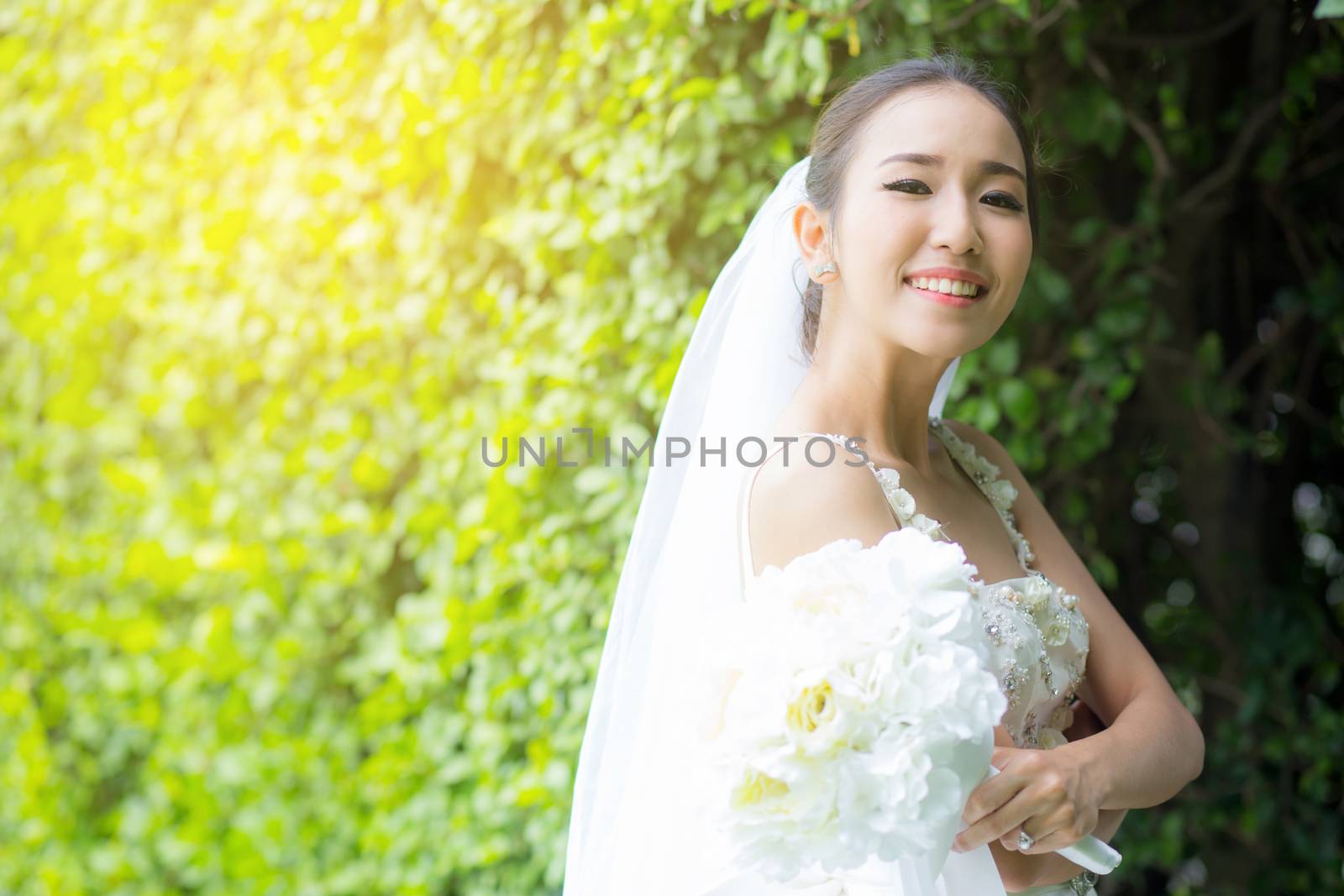 beautiful young woman on wedding day in white dress in the tree wall. Female portrait in the park - Selective focus