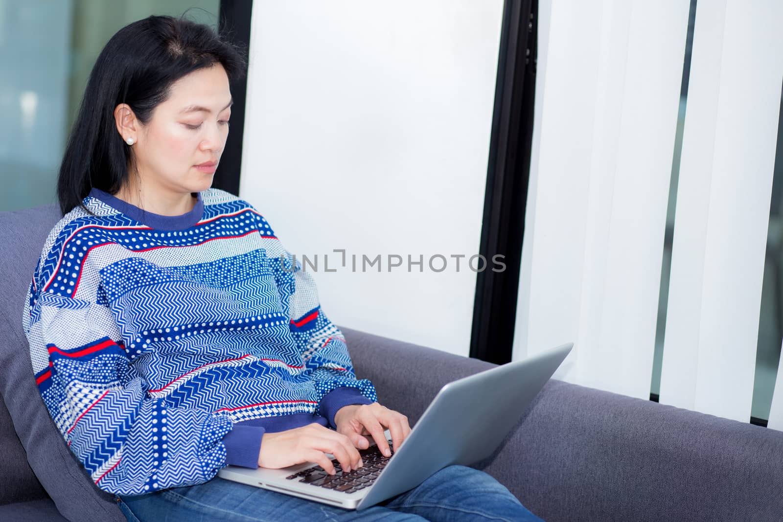 Closeup computer notebook on sofa with asian woman for work in l by nnudoo