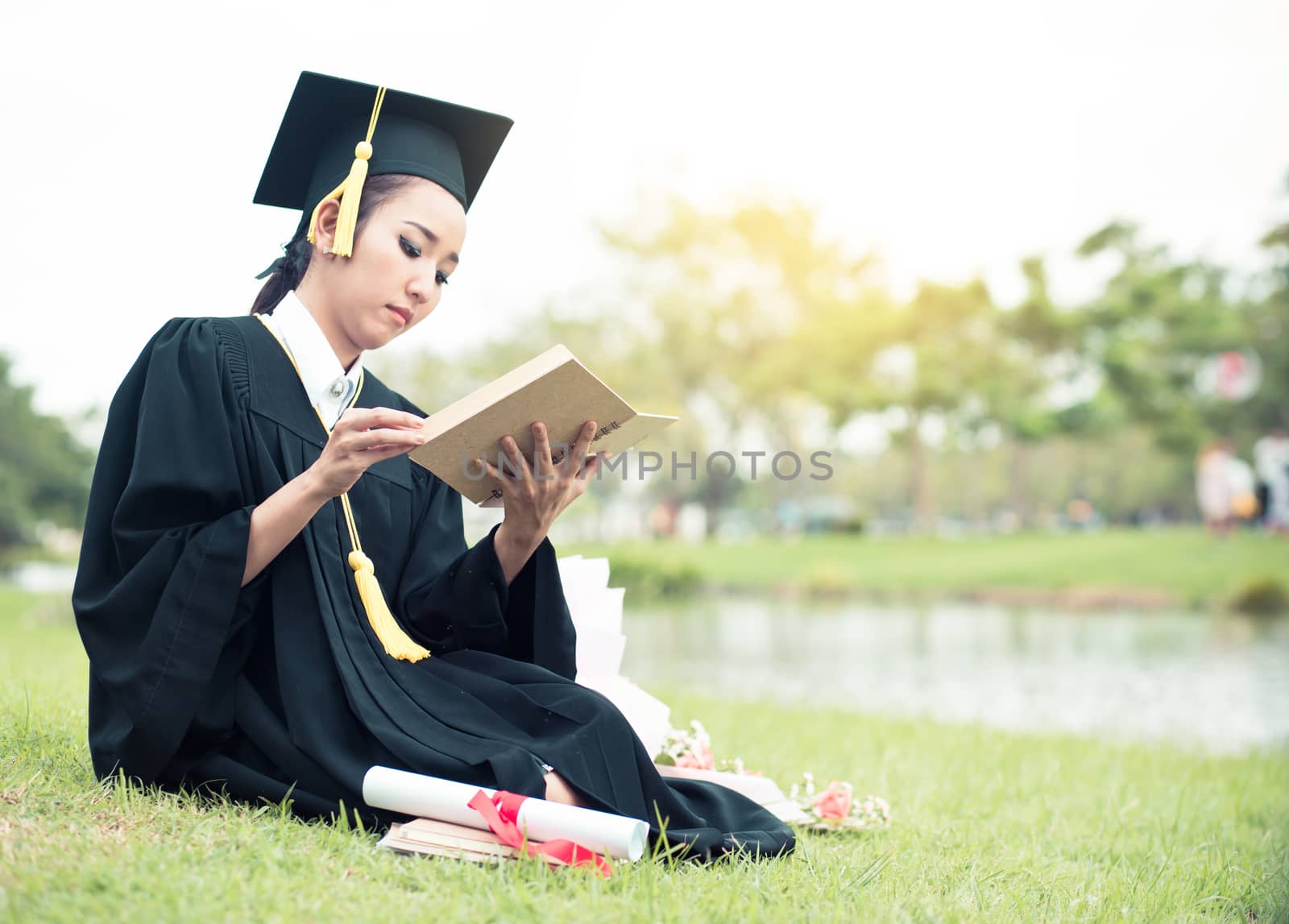 Graduate reading diary, notebook in her hand feeling relaxing and so happiness in commencement day