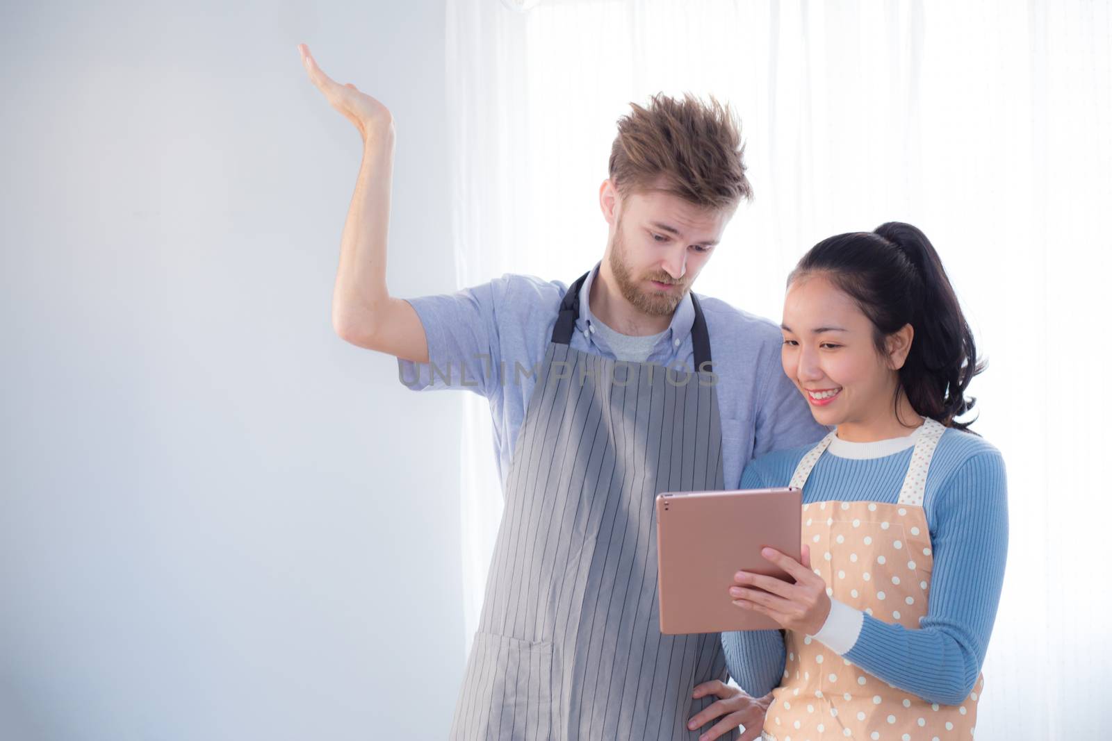 Young couple in kitchen looking at tablet - Man and girl using digital tablet in kitchen.