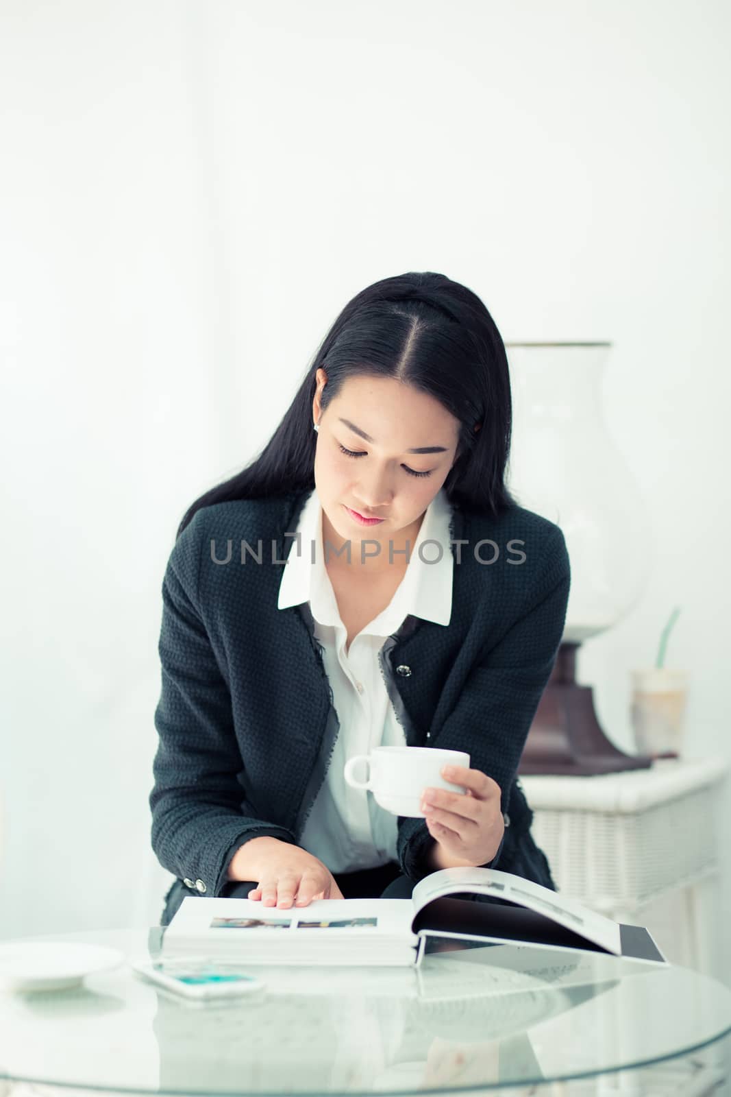 Young businesswoman sitting at table in coffee shop and reading book.