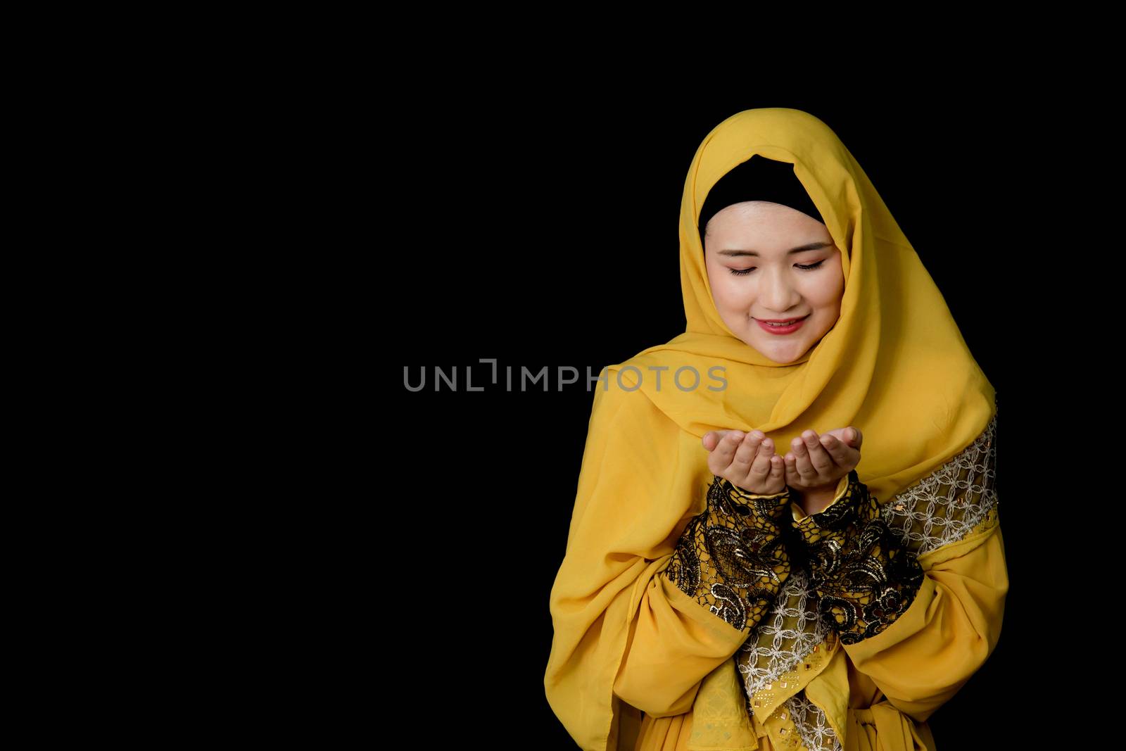 religious young Muslim woman praying over black background.
