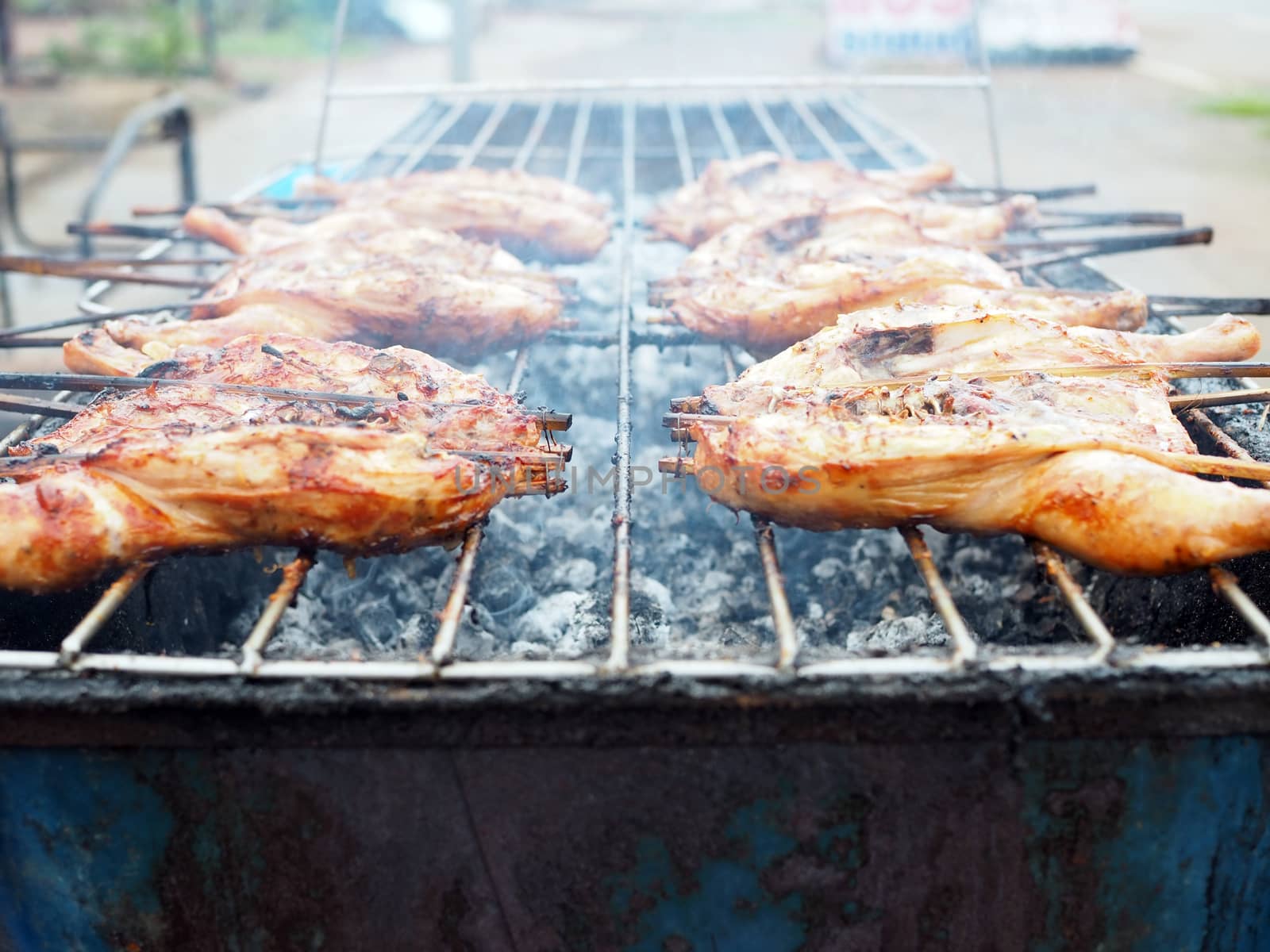 Grilled chicken on an iron stove made from a bucket
Food concept