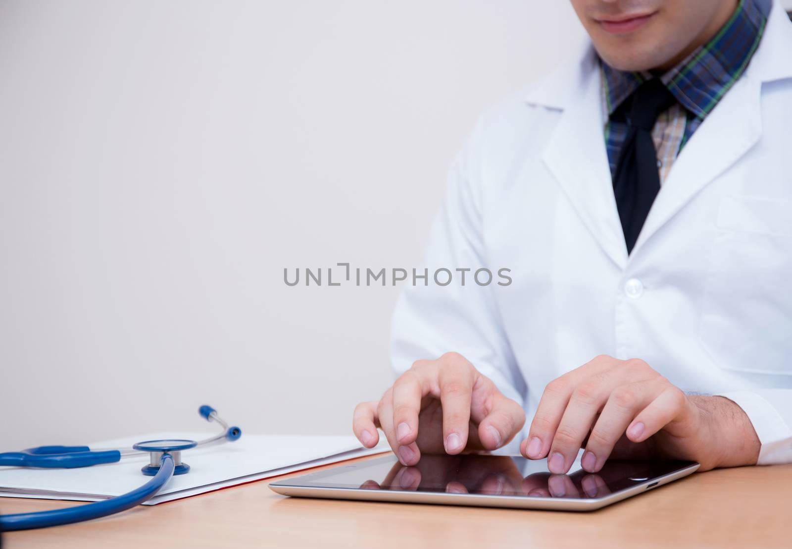 male doctor with tablet computer and stethoscope at the desk on white background.