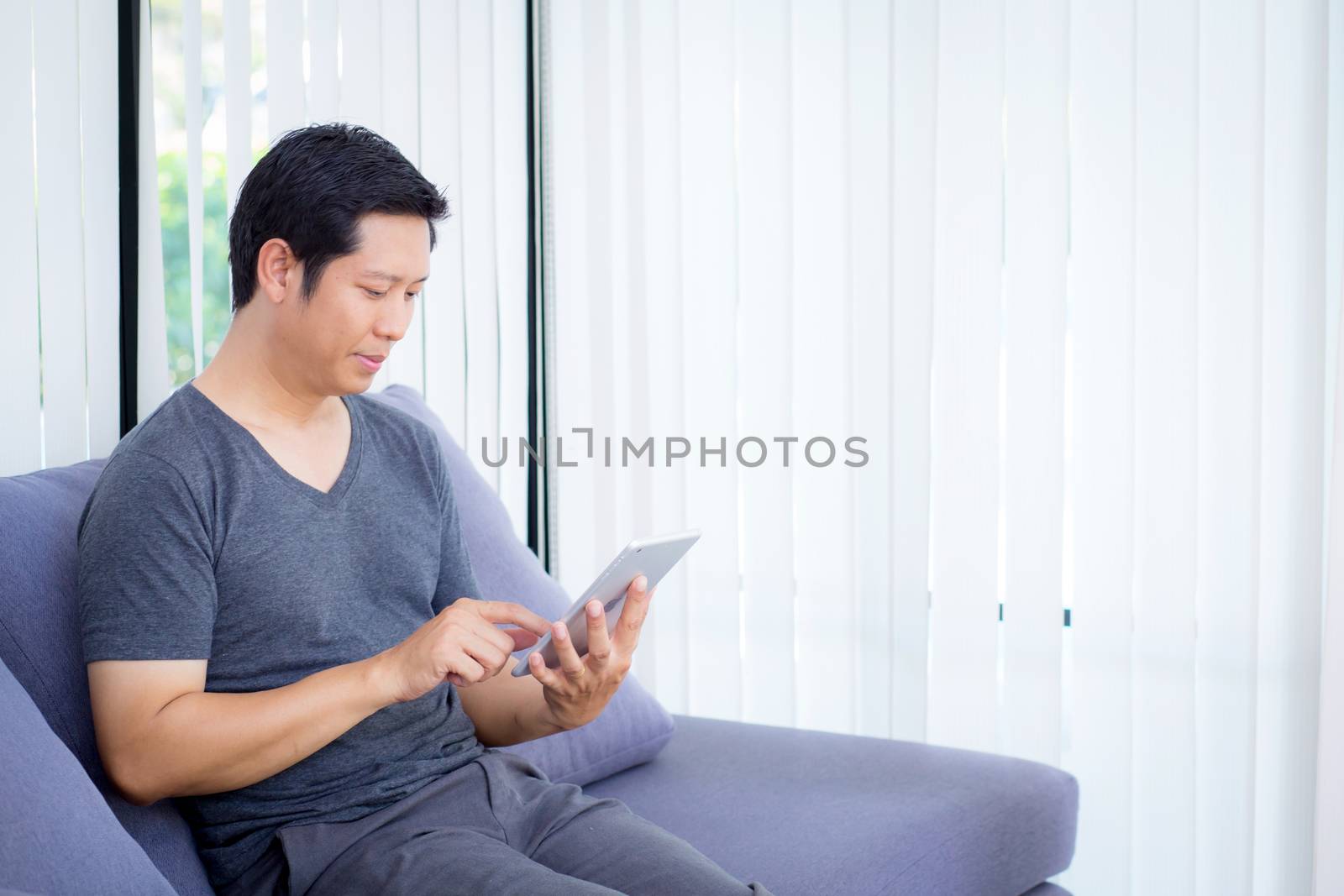 businessman watching media content in a tablet sitting on a sofa at home.