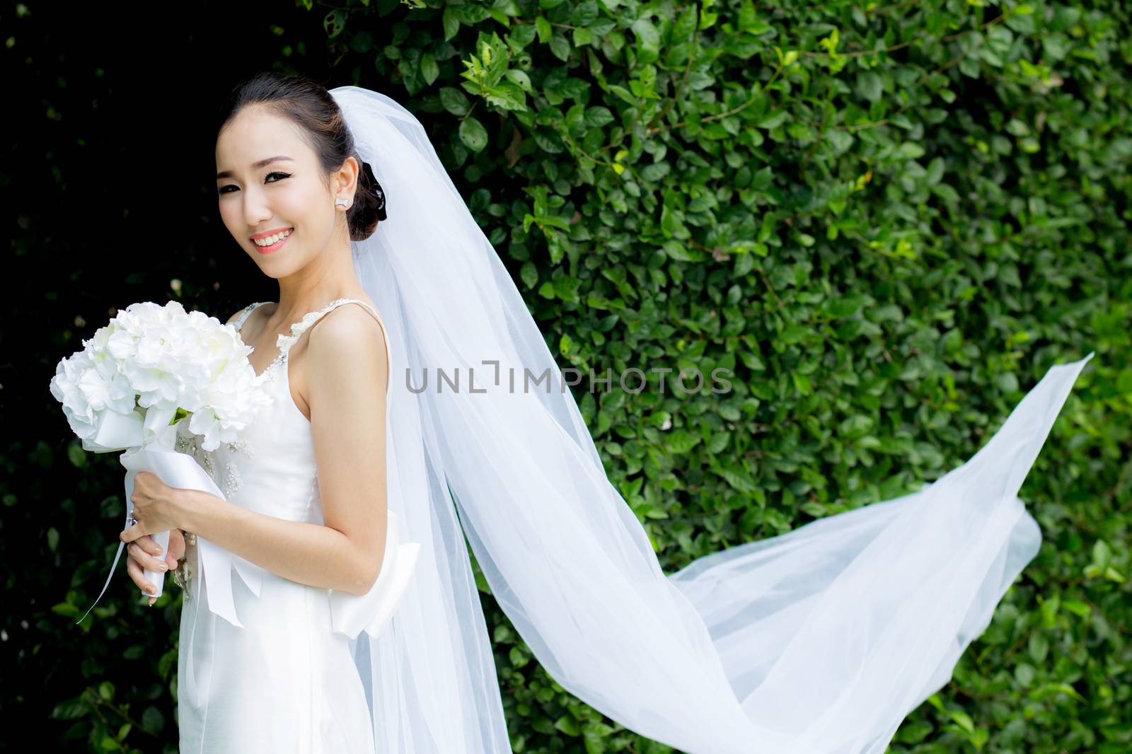 beautiful young woman on wedding day in white dress in the tree wall. Female portrait in the park - Selective focus.