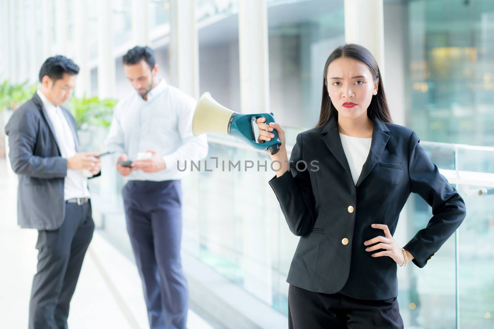 Young business woman working at the office holding megaphone.