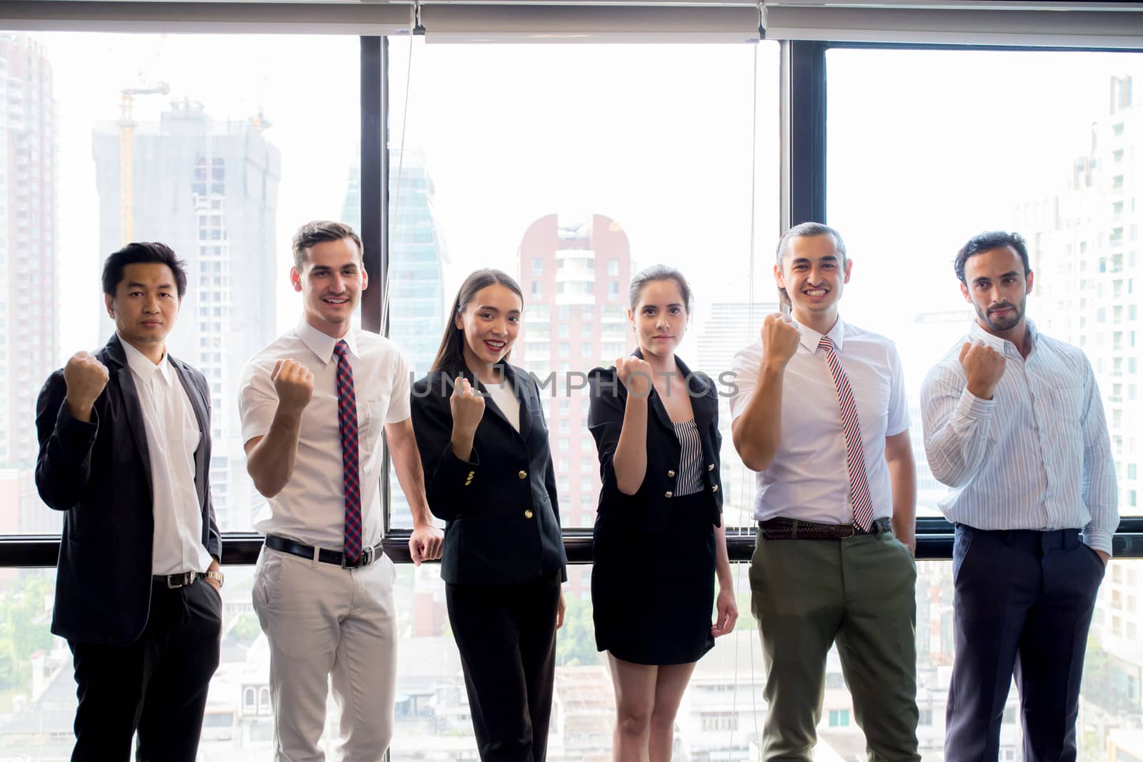 Portrait of happy business partners looking at camera with smiles and geture of teamwork.