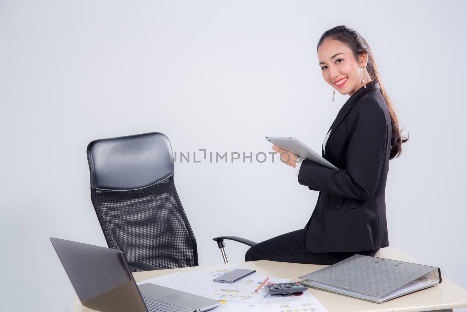 businesswoman looking tablet with sitting table in office on white background.