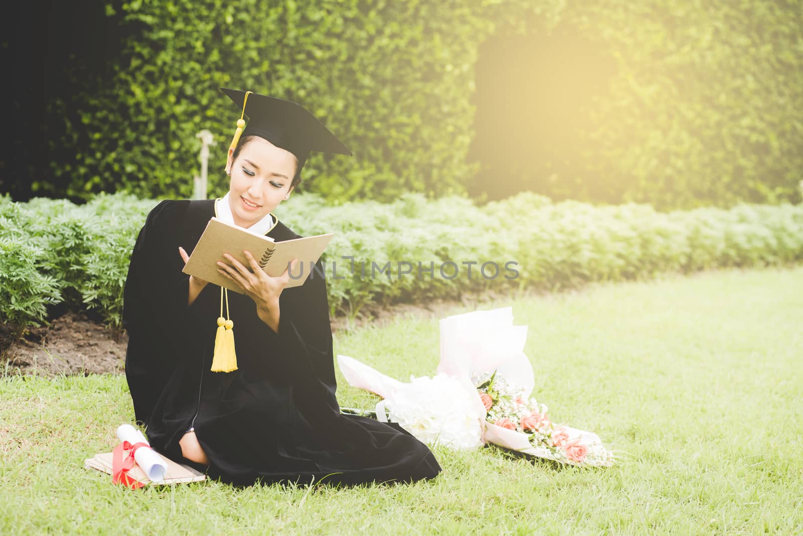 Graduate reading diary, notebook in her hand feeling relaxing and so happiness in commencement day