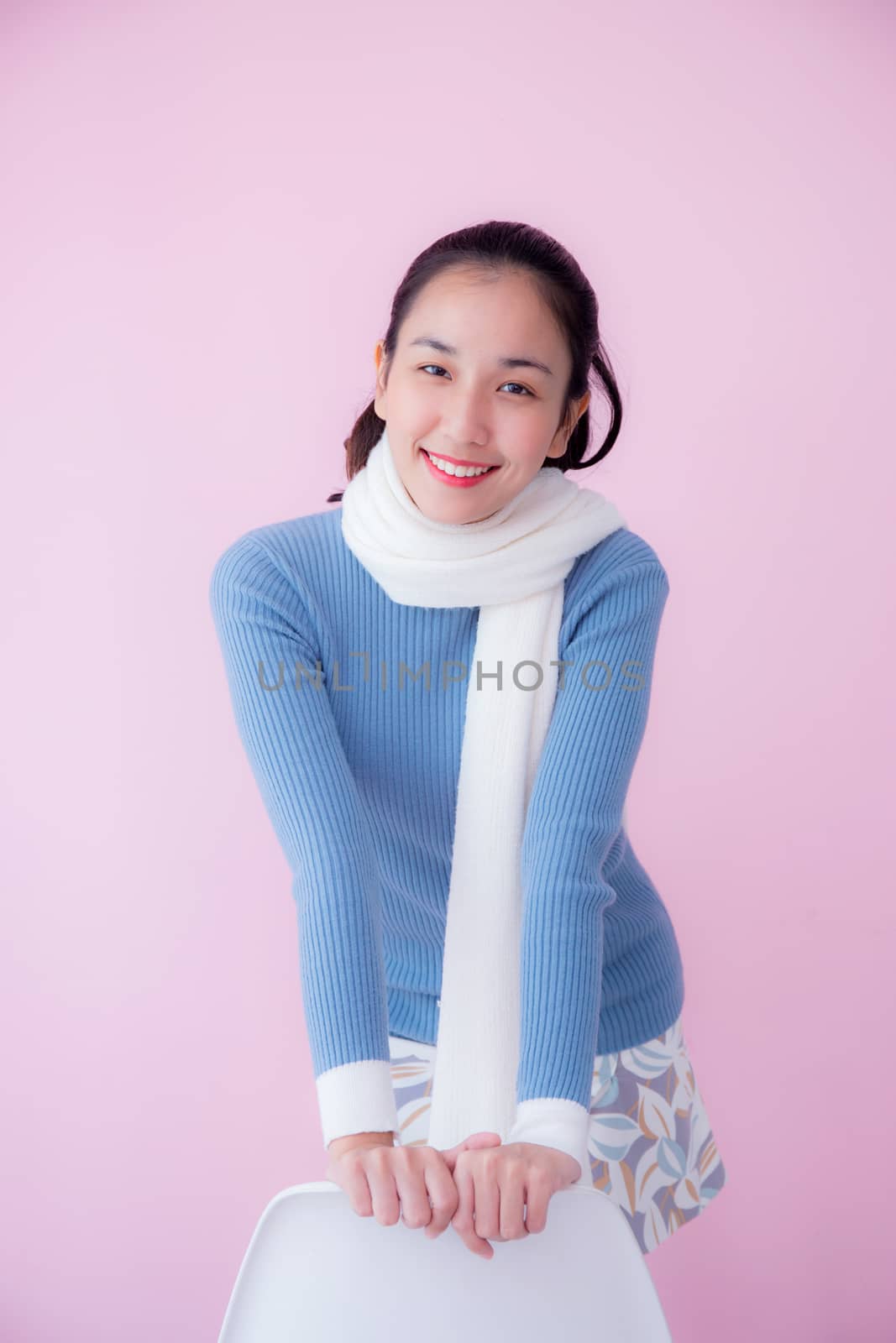 Happy beautiful young woman asian wearing scarf sitting on living room pastel color tone.