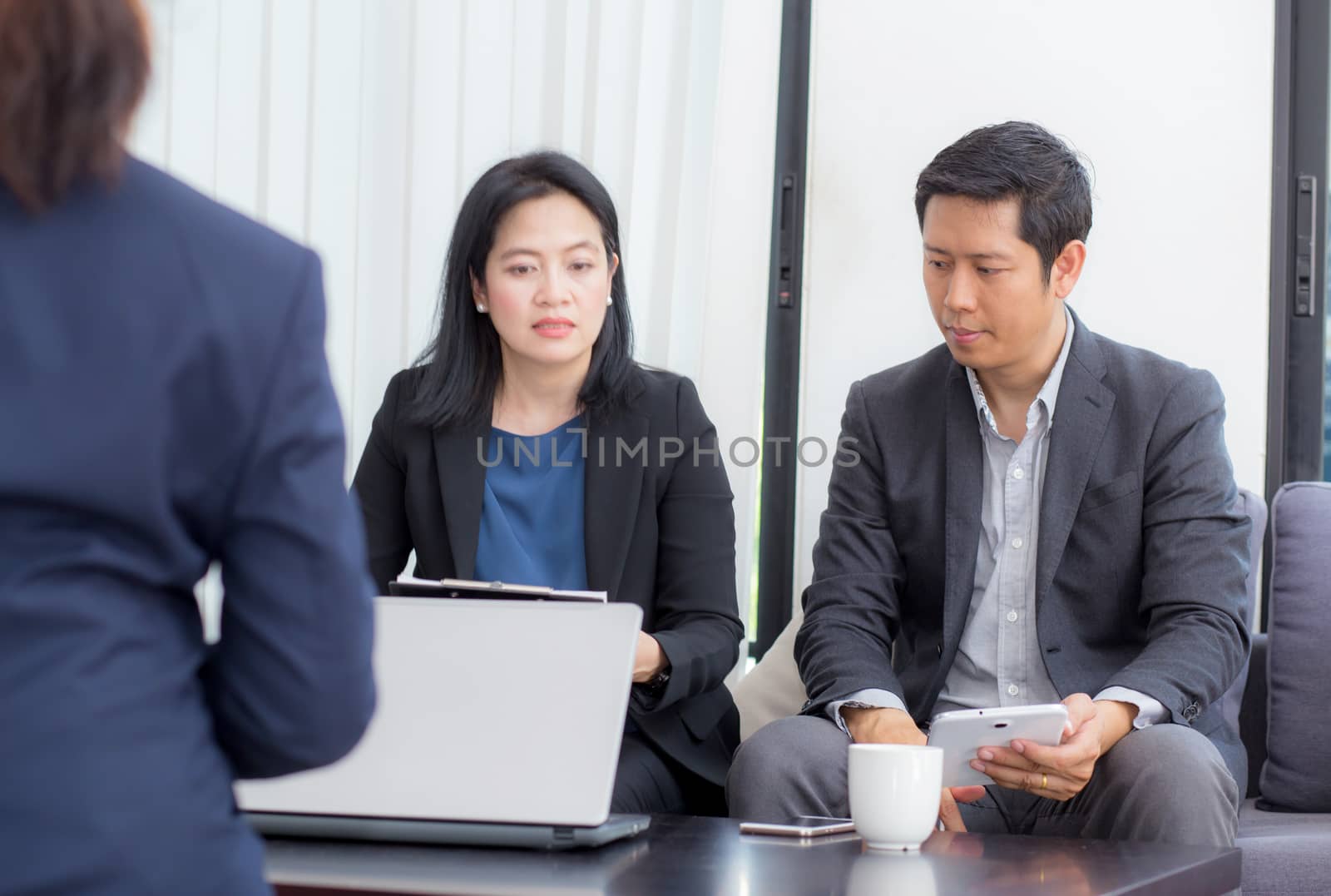 Team of business three people working together on a laptop with during a meeting sitting around a table.