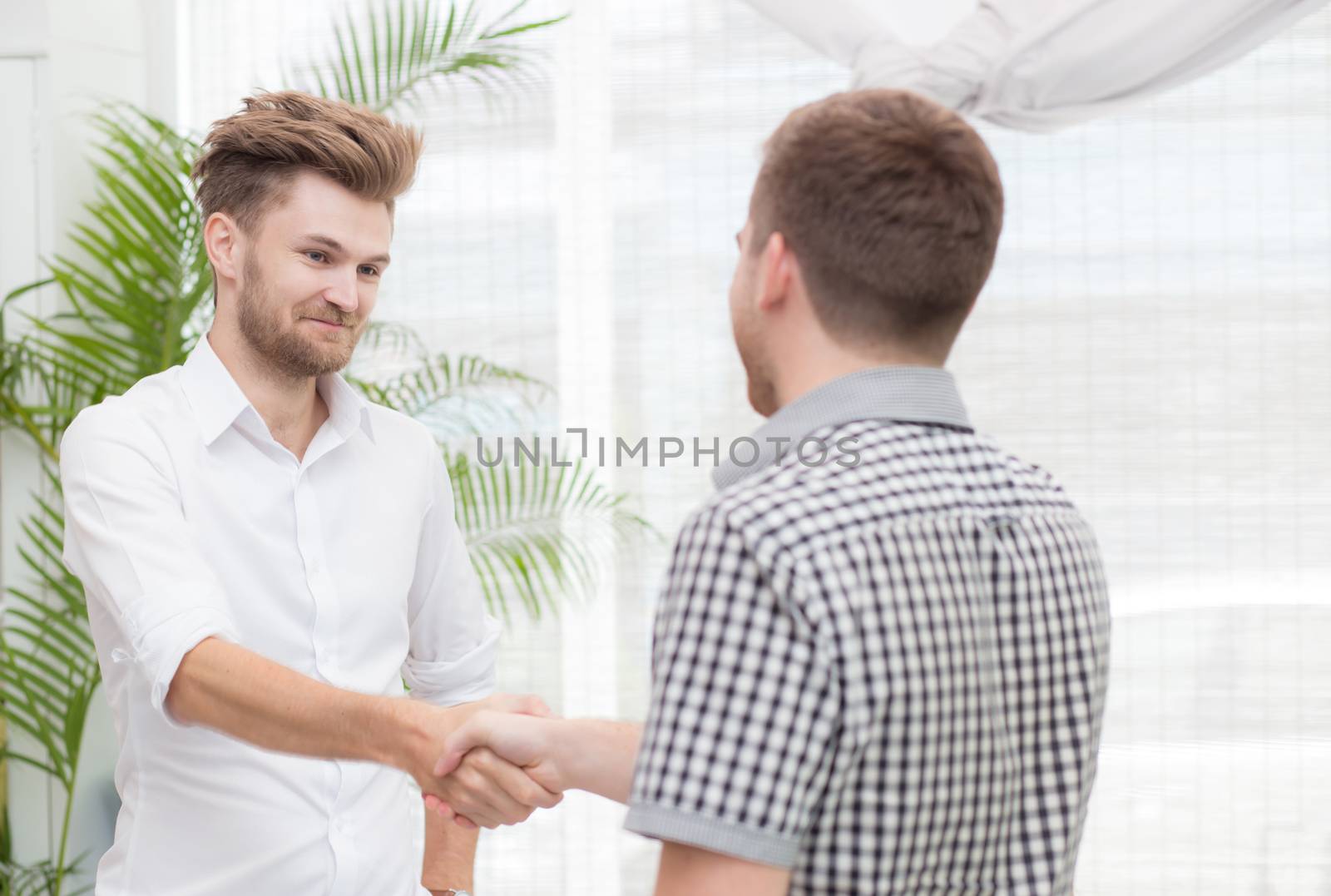 Two business colleagues handshake during meeting. by nnudoo