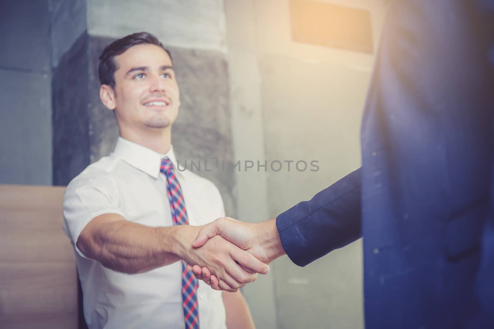 Two happy successful business partner shaking hands in the offic by nnudoo