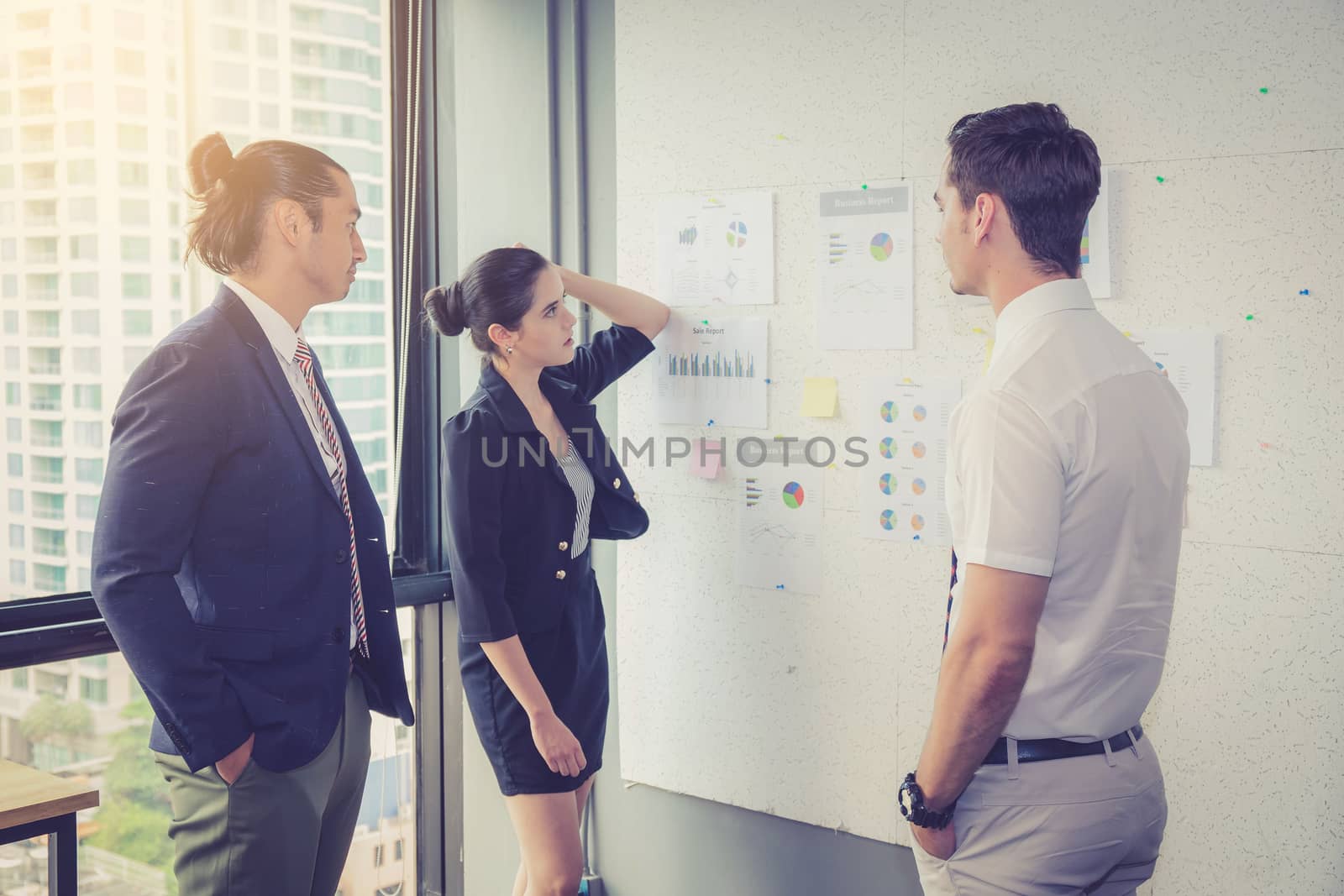 Three business people in modern office looking report and analyzing with talking in meeting room.