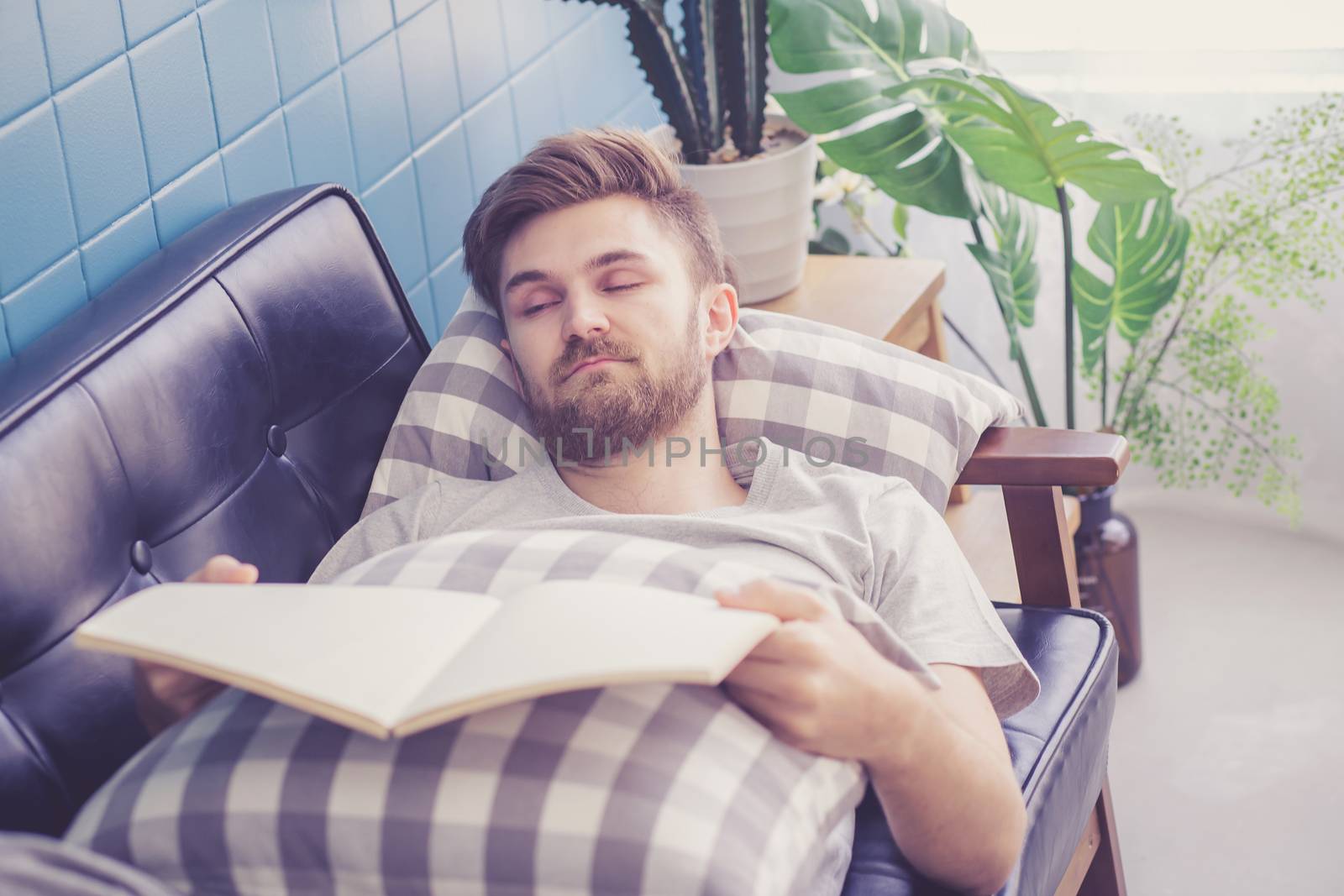 Man reading book with holding hand sleep in couch sofa.