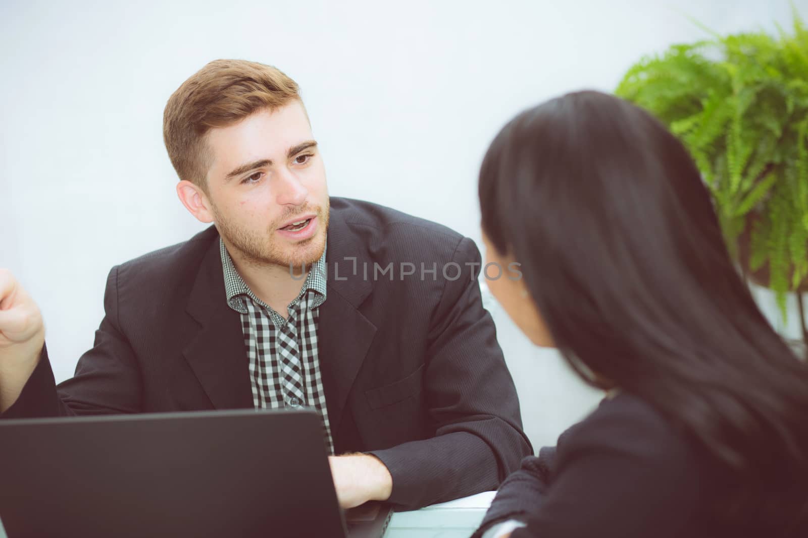 Couple of young business working at modern office, two coworkers discussing fun project over a laptop.