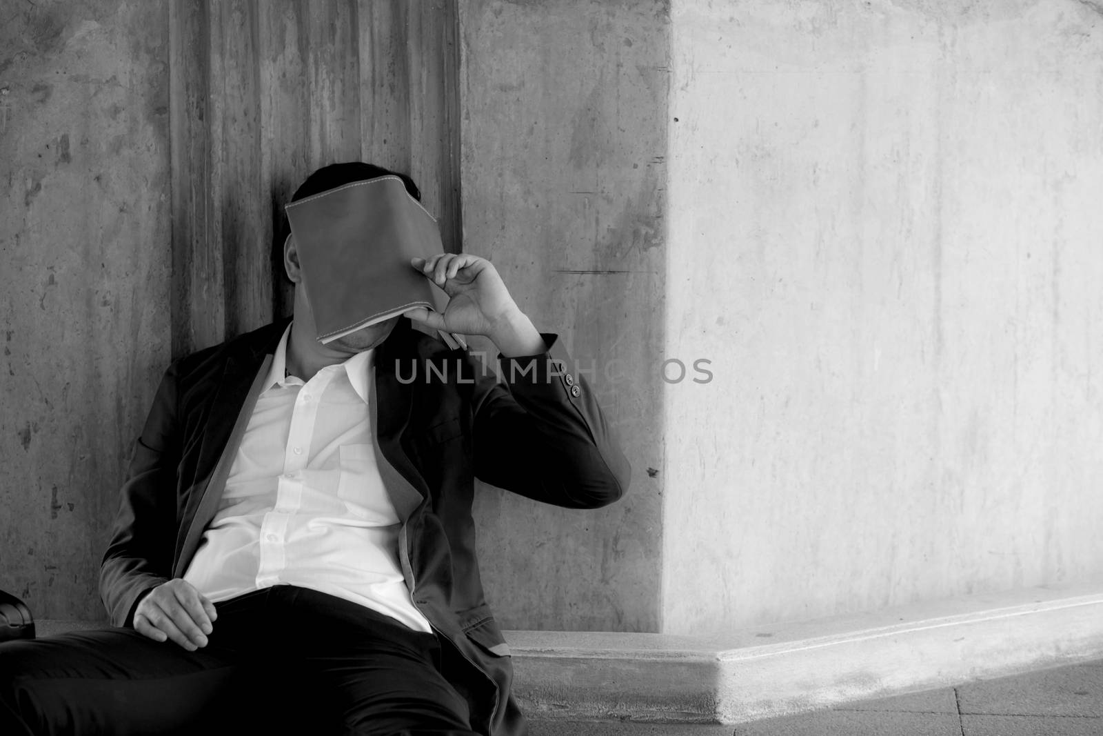 Stressed asian businessman bankrupt with sitting at outdoor and book close face black and white picture.