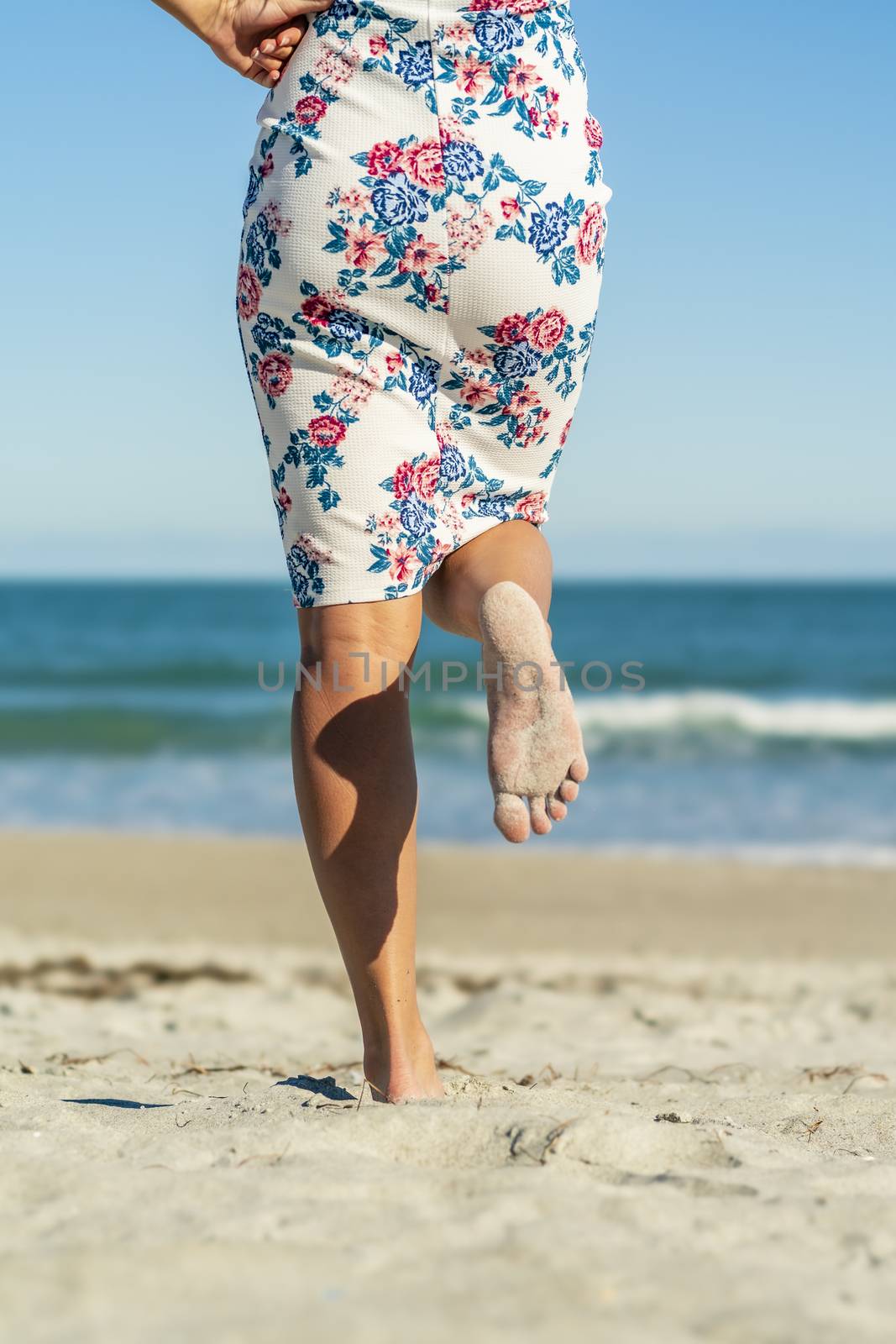 A gorgeous model walks in the sand at the beach on a beautiful day