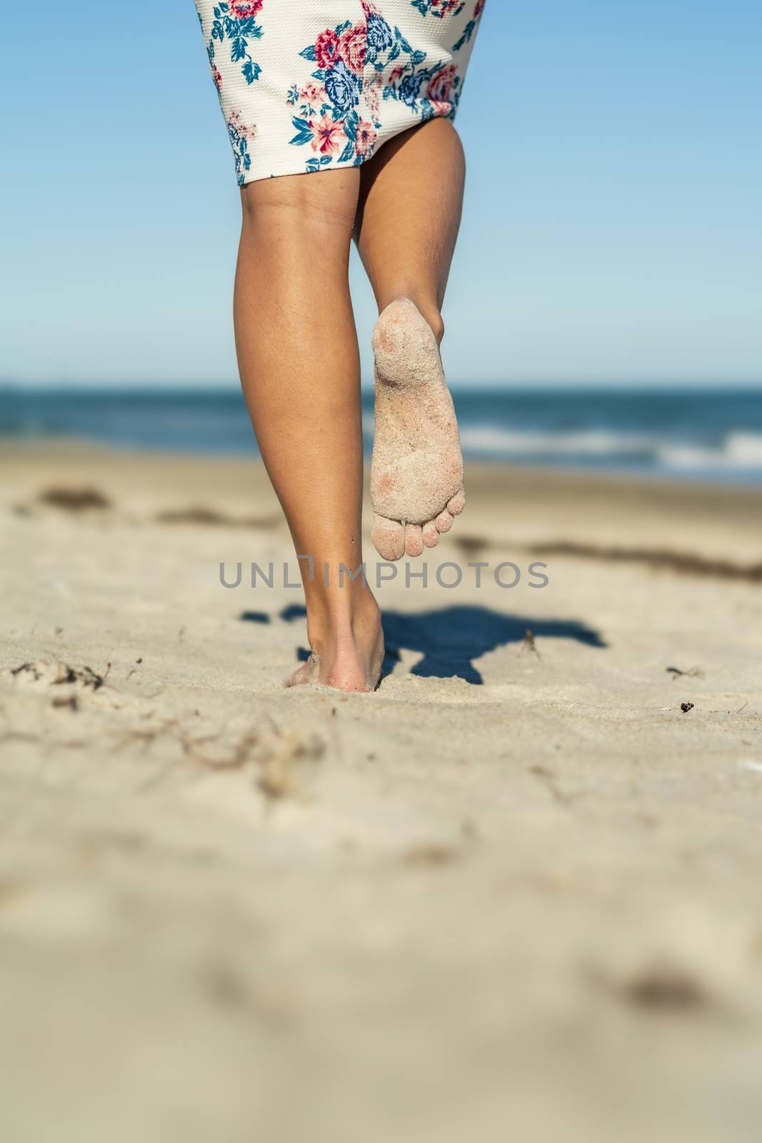 A gorgeous model walks in the sand at the beach on a beautiful day