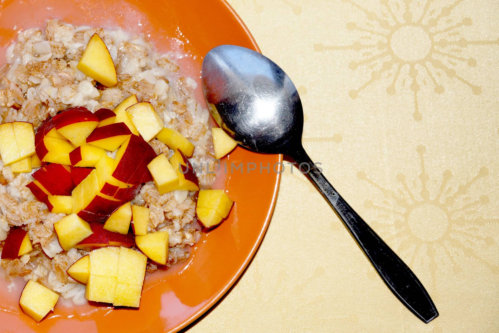 oatmeal porridge with chopped fresh peach in a plate with a spoon, vegetarian breakfast. by Annado