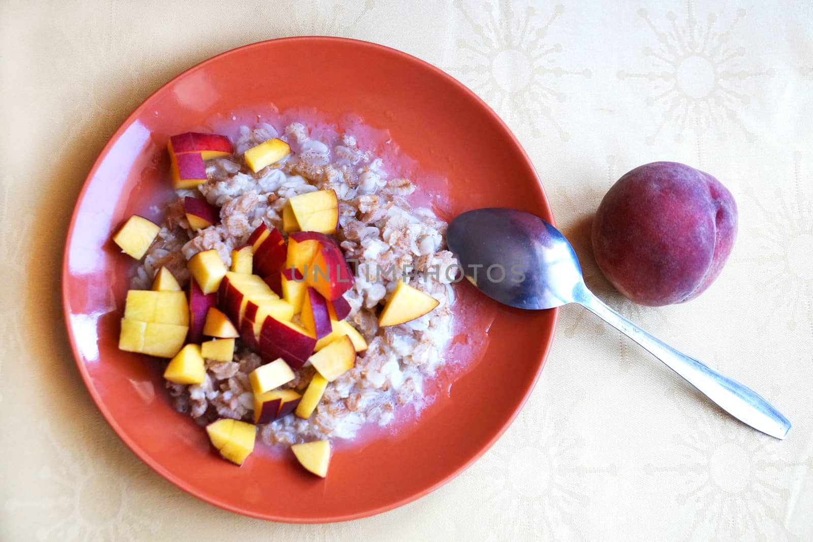 oatmeal porridge with chopped fresh peach in a plate with a spoon, vegetarian breakfast. by Annado