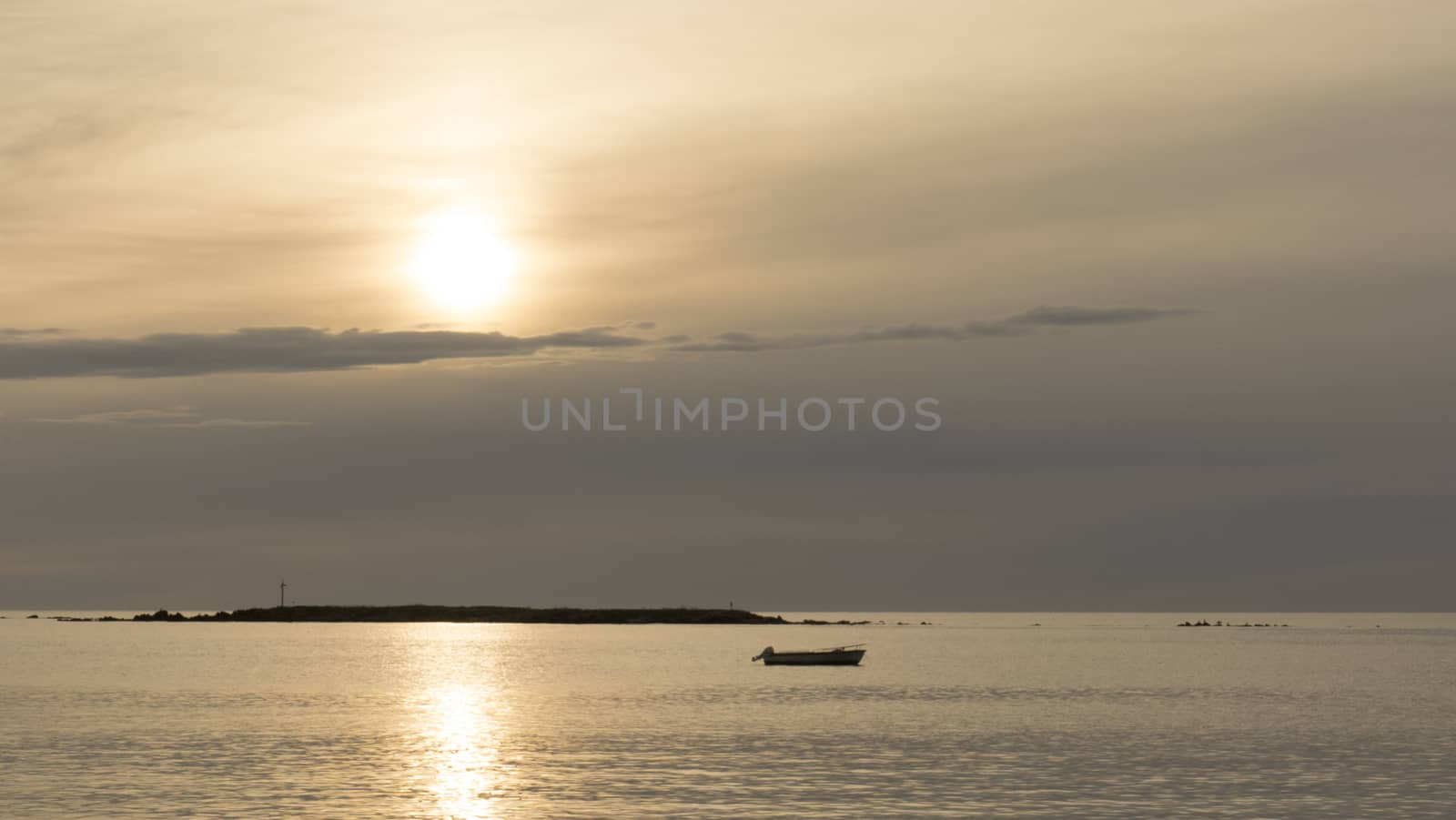 a fishing boat anchored in a bay at sunrise or sunset in backlight with cloudy sky