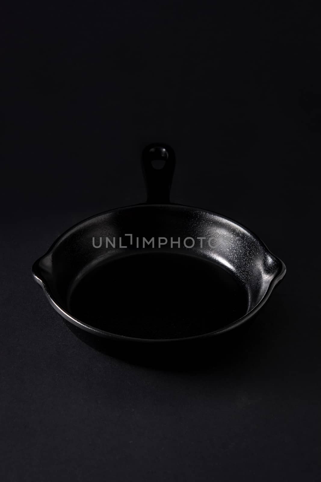 Empty black frying pan on black background