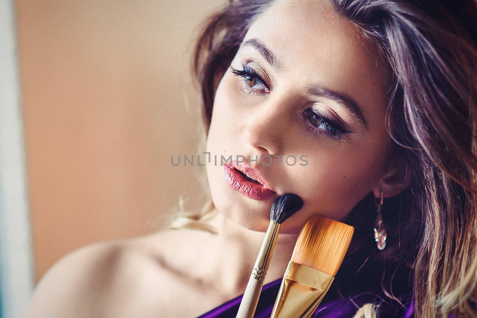 model girl in a blue dress in an art workshop with brushes, a palette and paintings