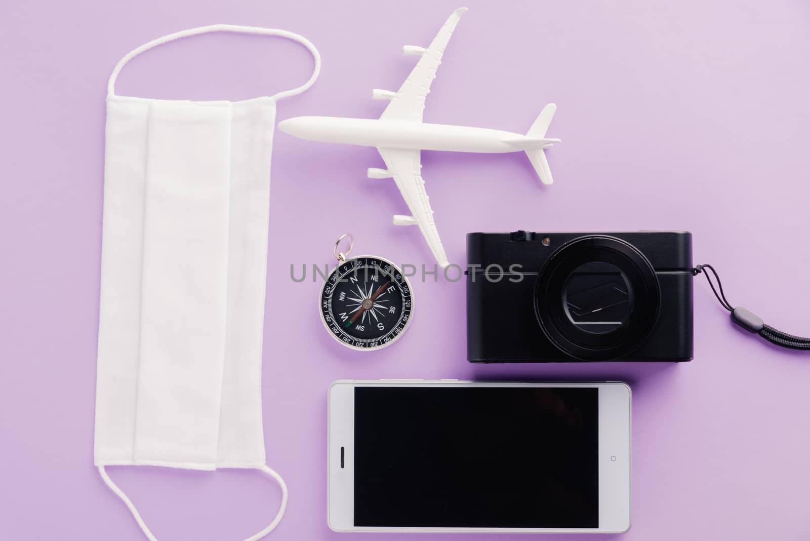 World Tourism Day, Top view of minimal model plane, airplane, starfish, compass, smartphone blank screen and face mask isolated on purple background, accessory flight holiday under coronavirus concept