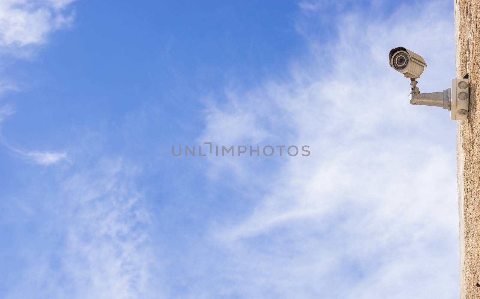View of house wall with surveillance security camera and blue cloudy sky background