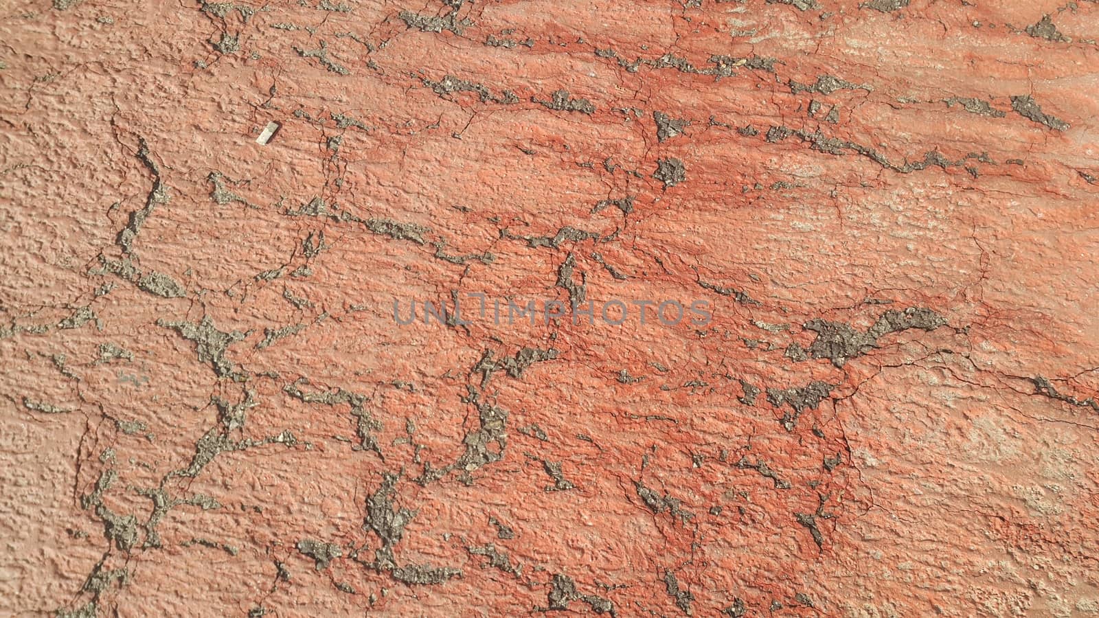 Red colored damaged road or paved pathway with crackes of different shpaes. Cracked texture with copy space for text and messages