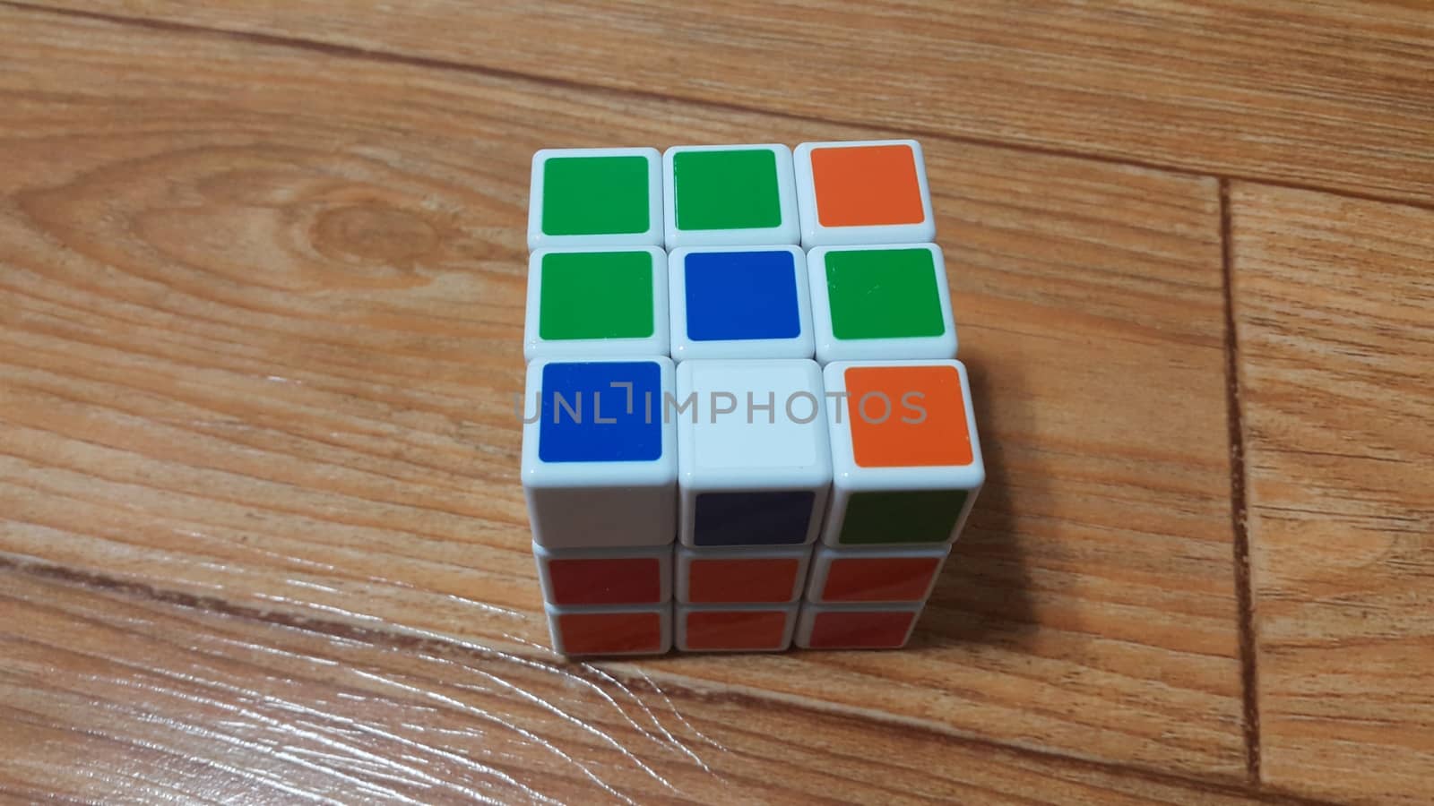Close up view of Rubik cube on wooden floor by Photochowk