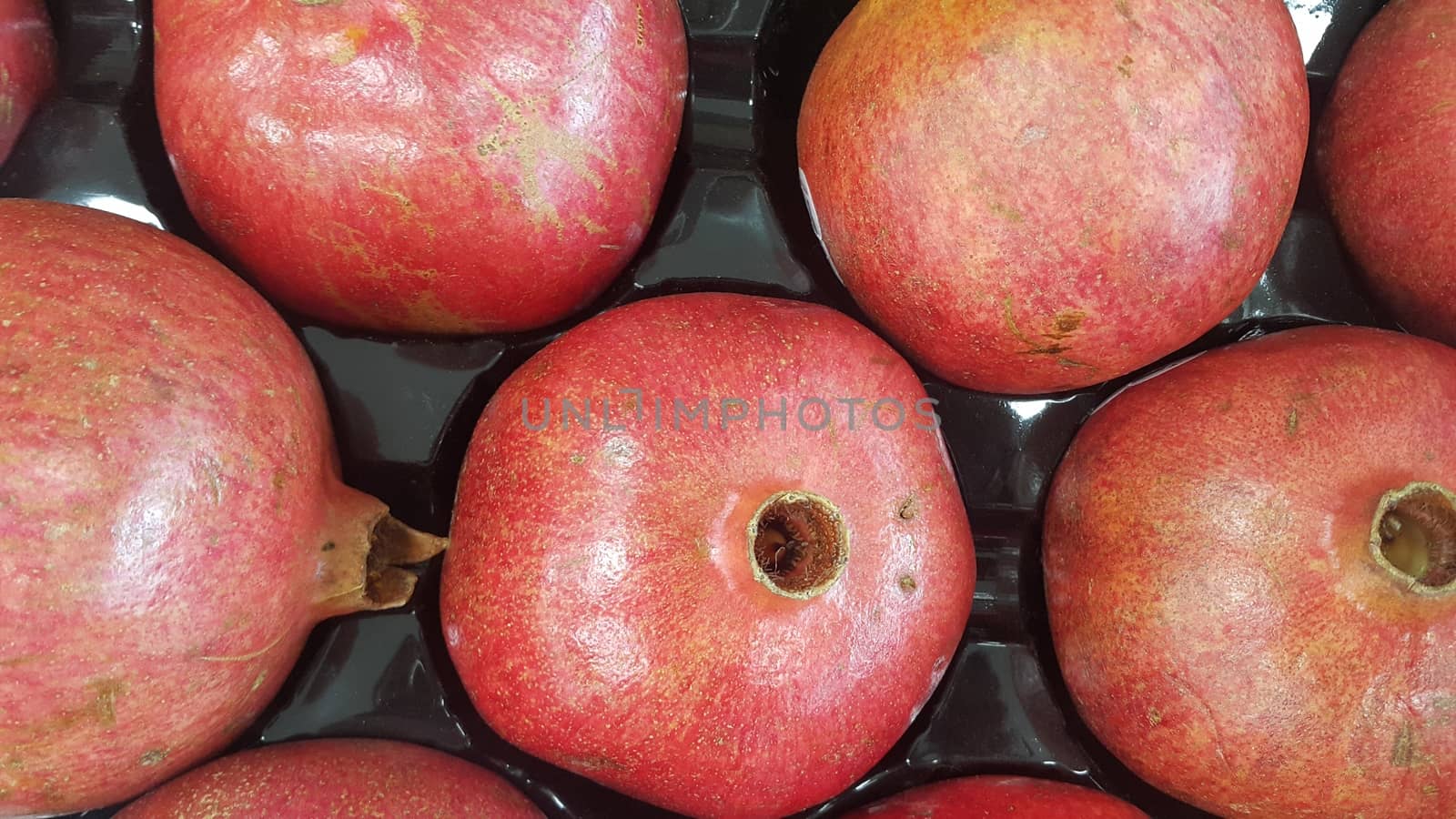 Fruit background: Large pile of  red pomegranate in supermarket. It is full of vitamins, minerals, fiber and antioxidants.