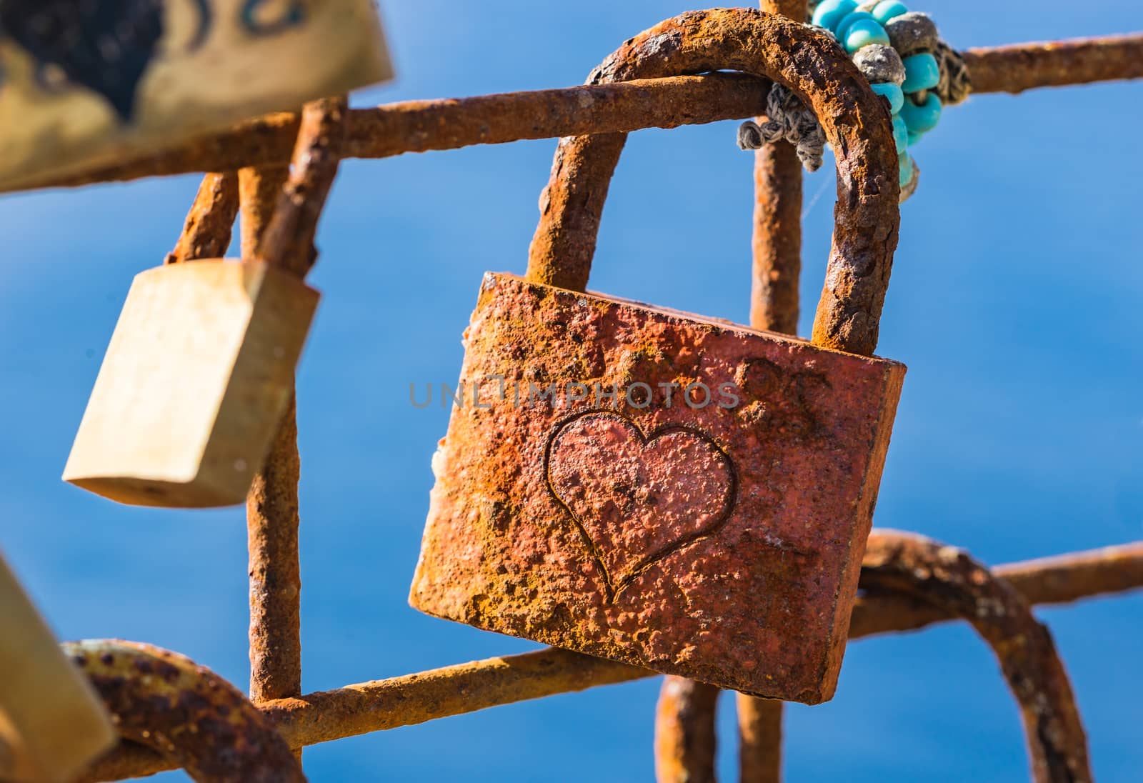 Old rusty love lock hanging on fence