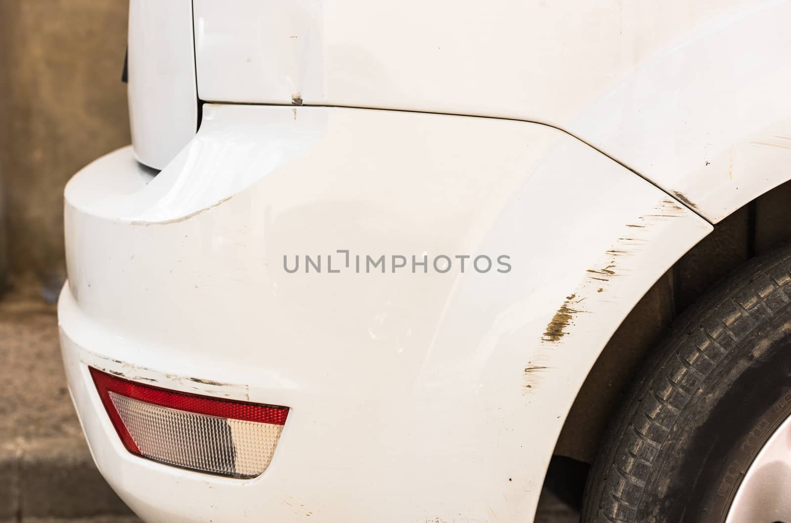 Car accident with detail view of damaged scratched bumper and fender