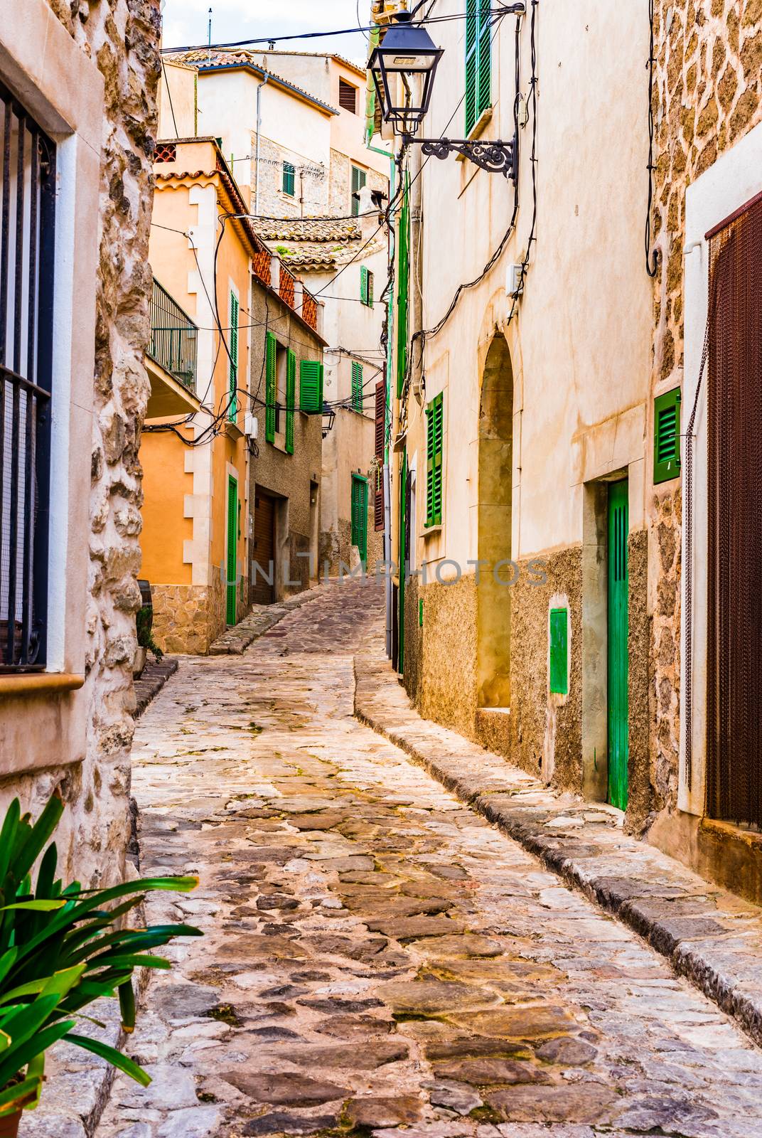 Old spanish village houses and cobblestone street by Vulcano