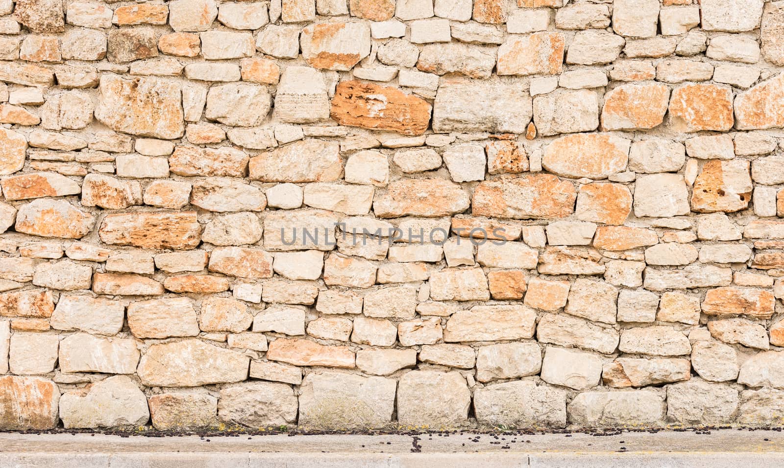 Rustic old stone wall background texture with sidewalk