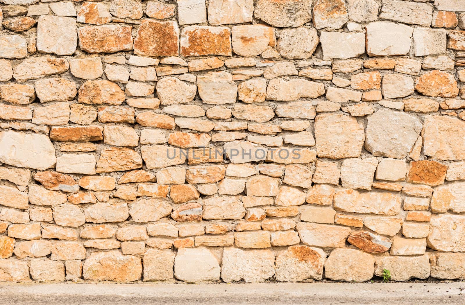 Old stone wall texture background with sidewalk