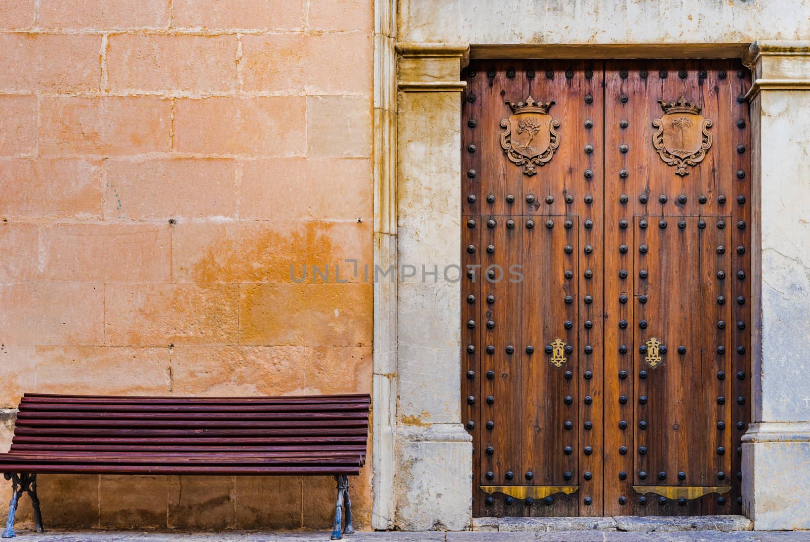Detail view of an old elegant wooden gate and bench in front of wall background