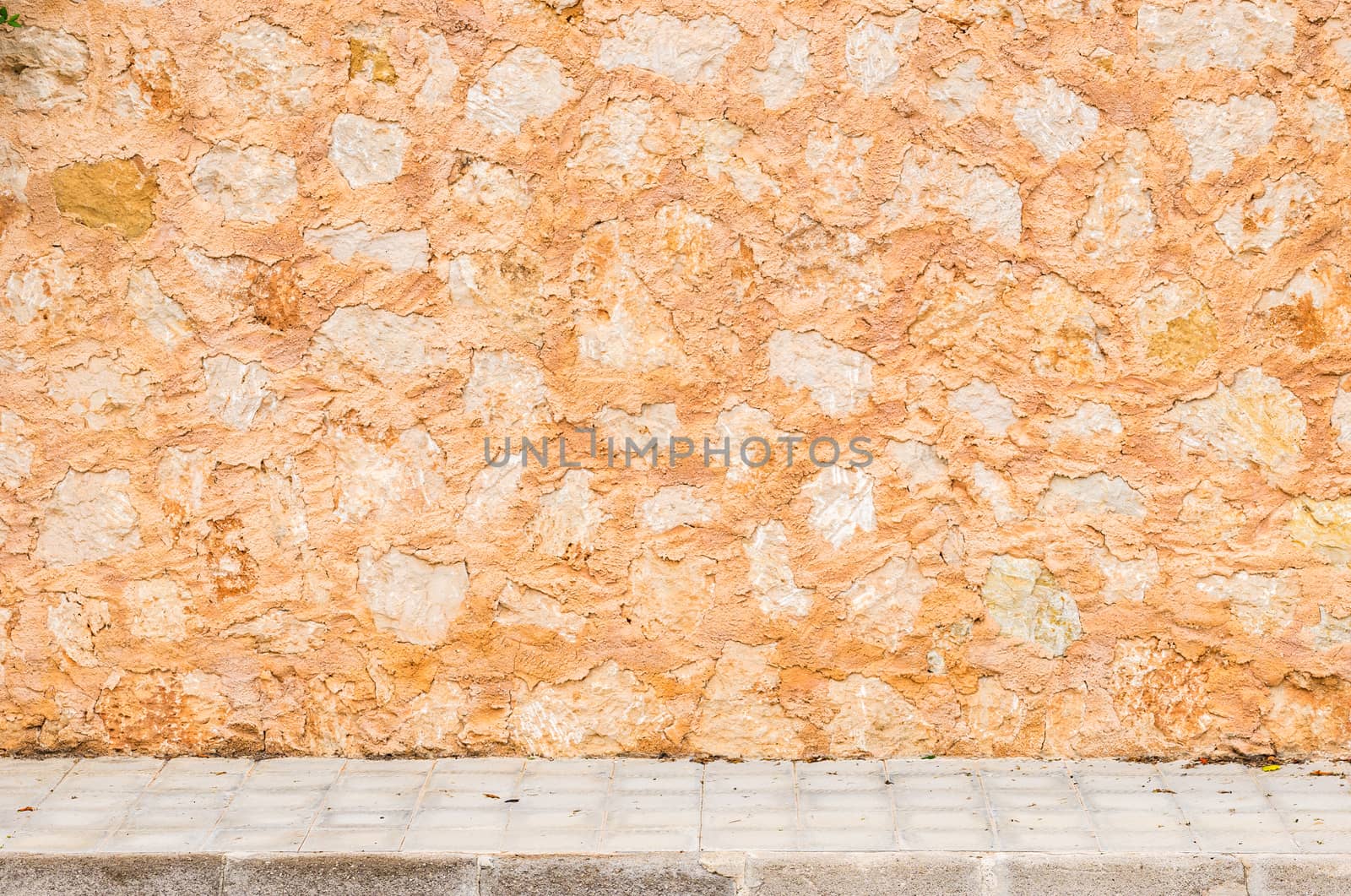 Rustic old stone wall background texture with pavement