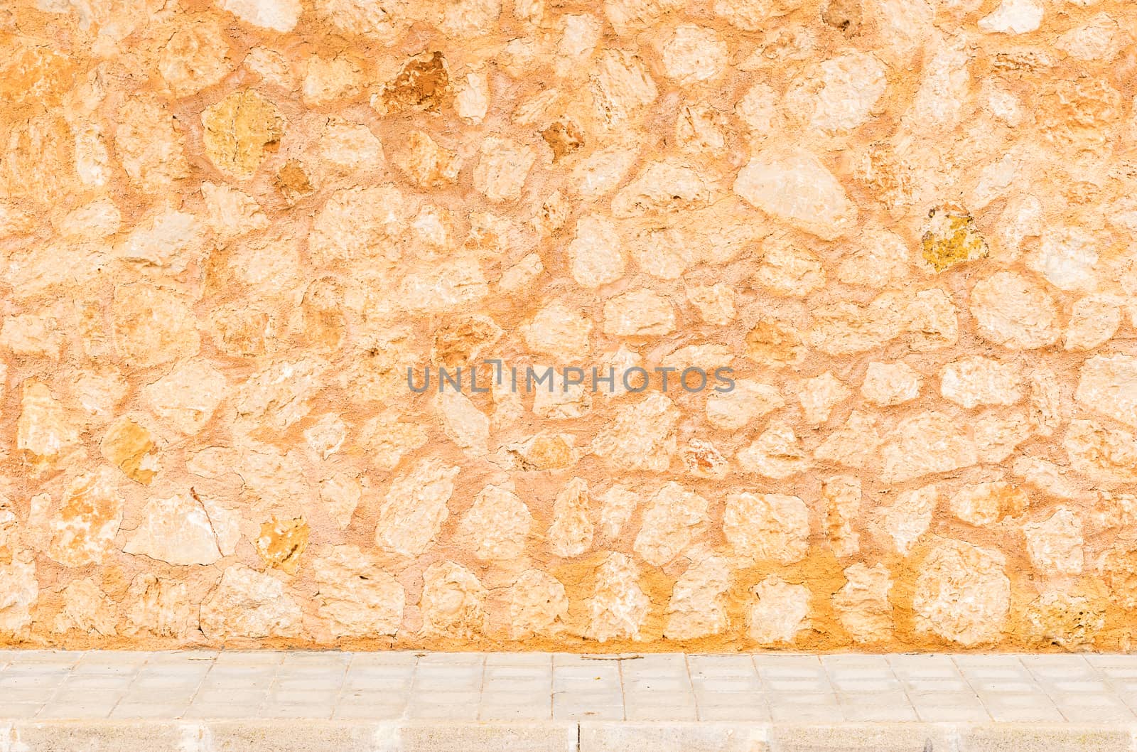Rustic stone wall background texture with sidewalk